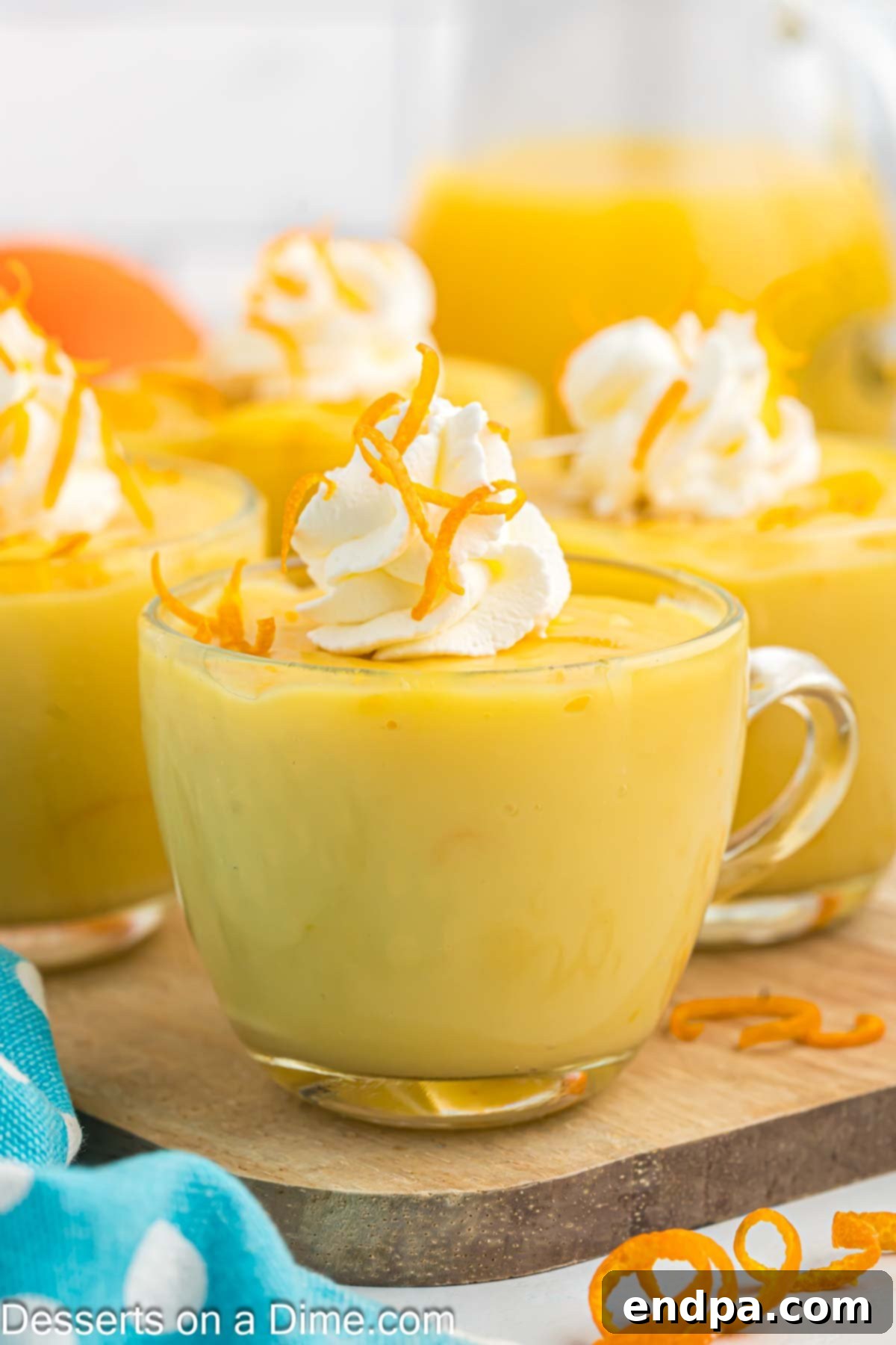 Orange Pudding in a glass topped with whipped cream.