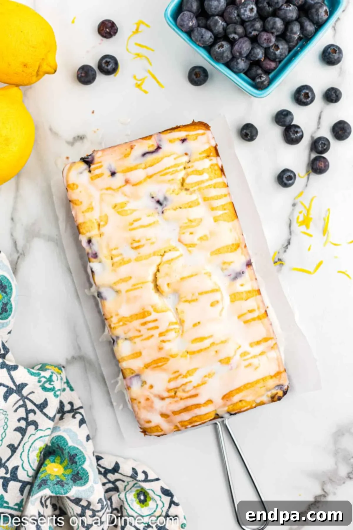Lemon glaze being drizzled generously over the cooled lemon blueberry bread.