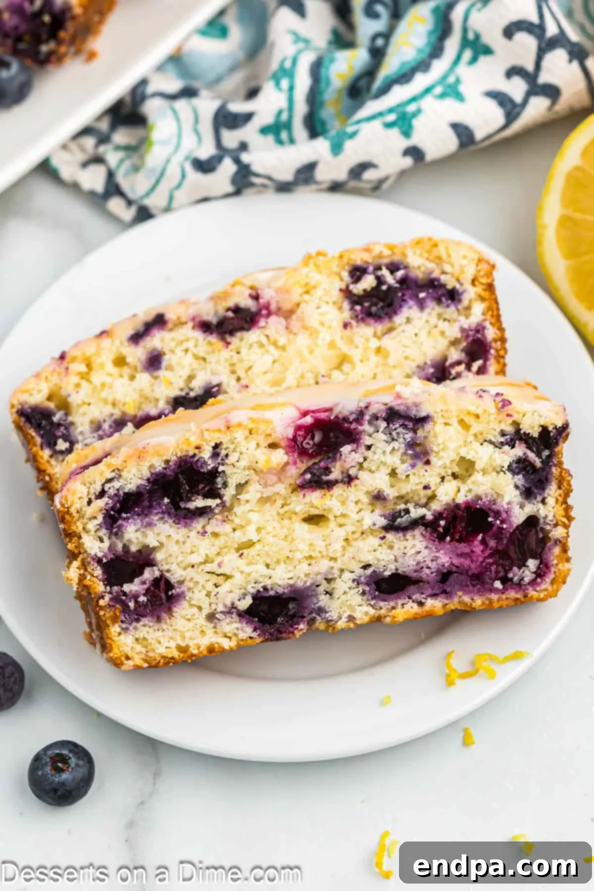 Close-up slices of Lemon Blueberry bread on a plate, showing the glaze and fruit.