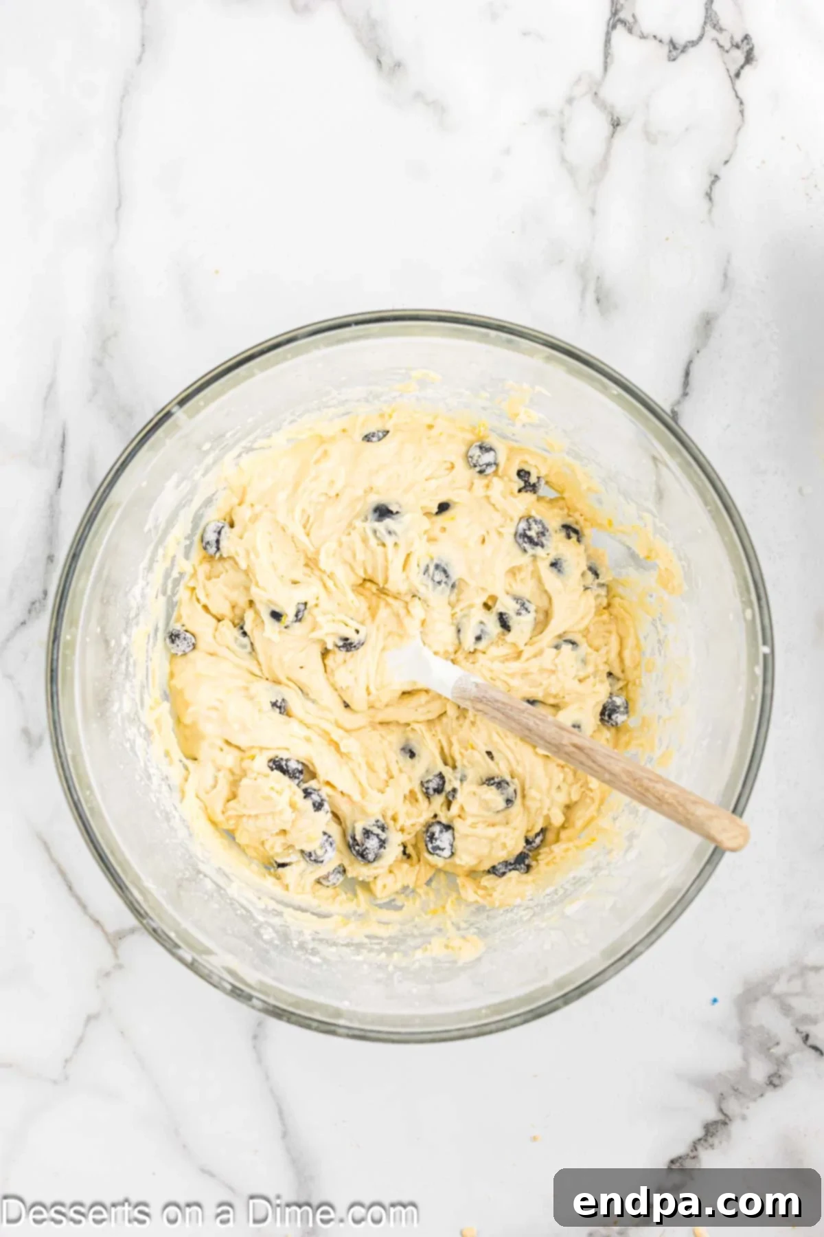 Blueberries folded into the bread mixture in a bowl.