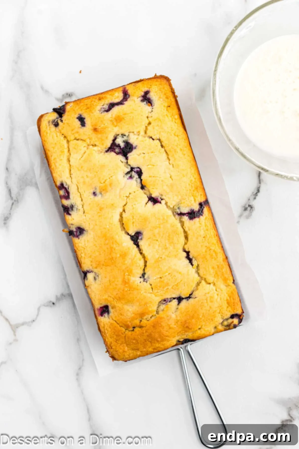 Loaf of lemon blueberry bread cooling on a wire rack.