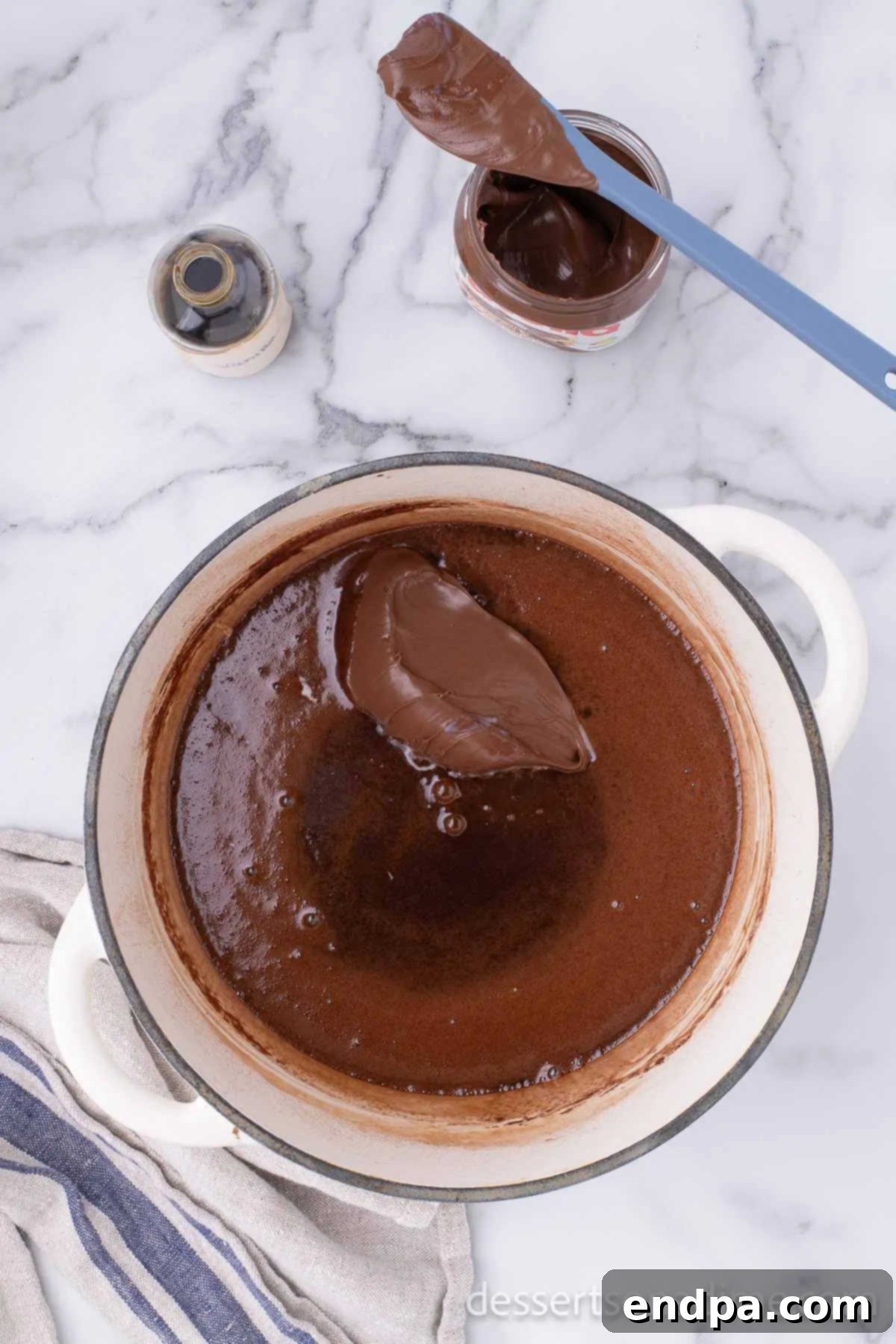 Nutella and vanilla extract added to the boiled mixture in the pan, ready to be stirred.