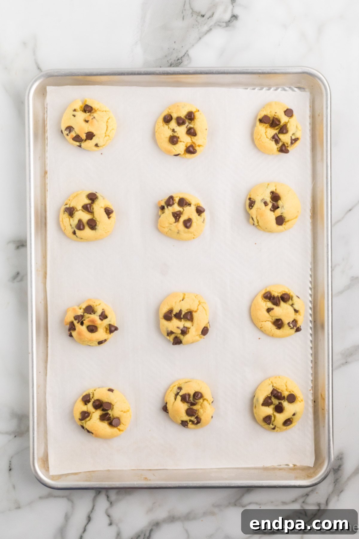 Irresistible Chocolate Chip Cake Mix Cookies 7 Freshly baked chocolate chip cake mix cookies cooling on a baking sheet, showing golden edges.