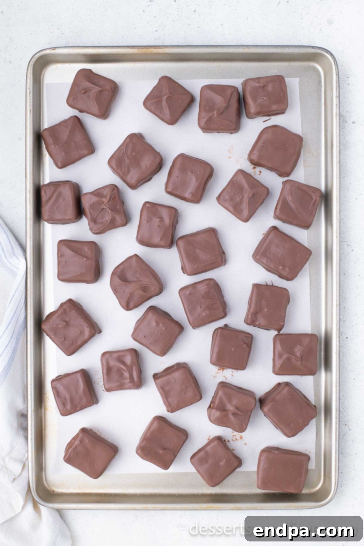 Chocolate-dipped squares placed back on a baking sheet to set in the freezer.