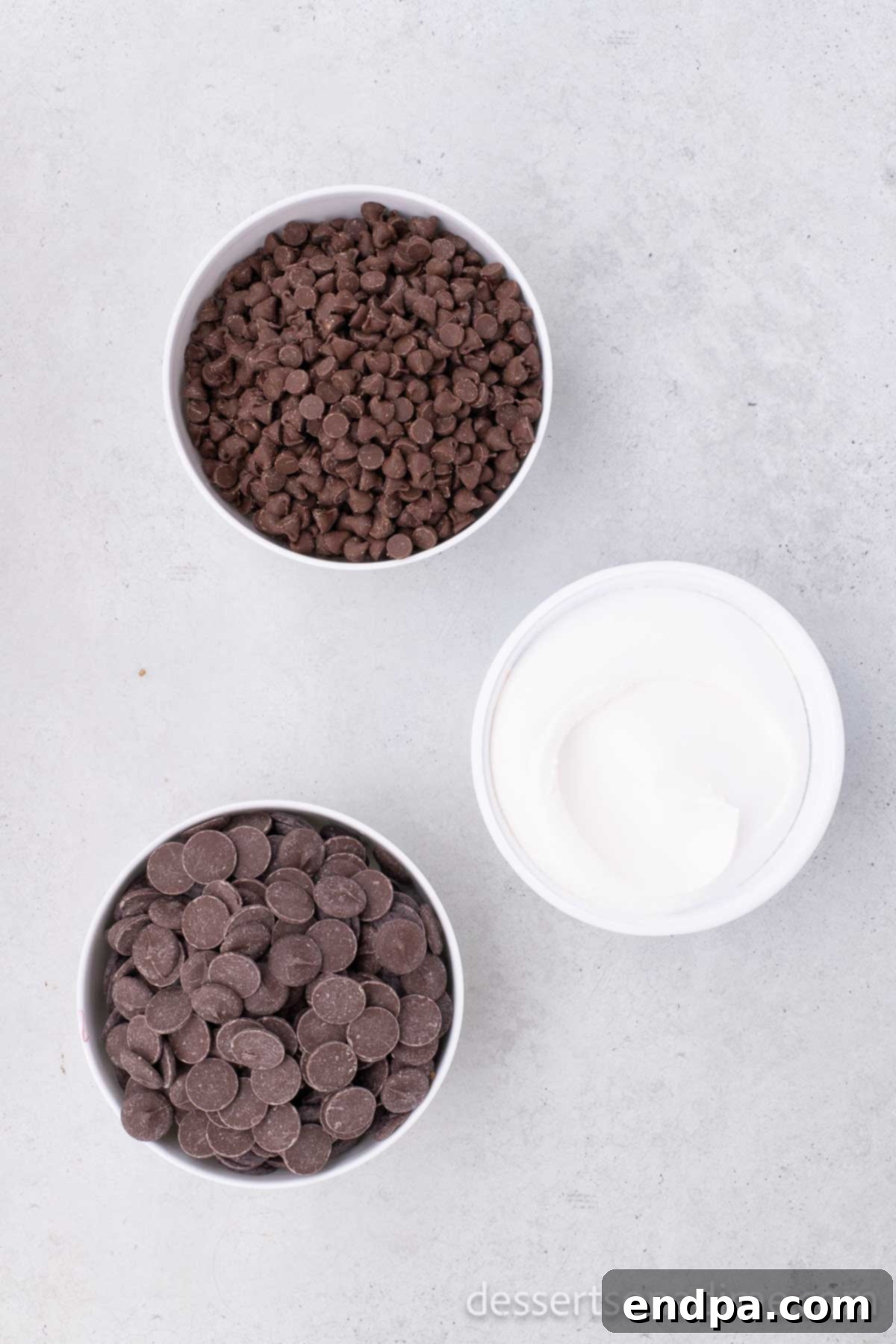 Ingredients for cool whip candy - milk chocolate chips, cool whip and chocolate melting wafers displayed on a wooden surface.