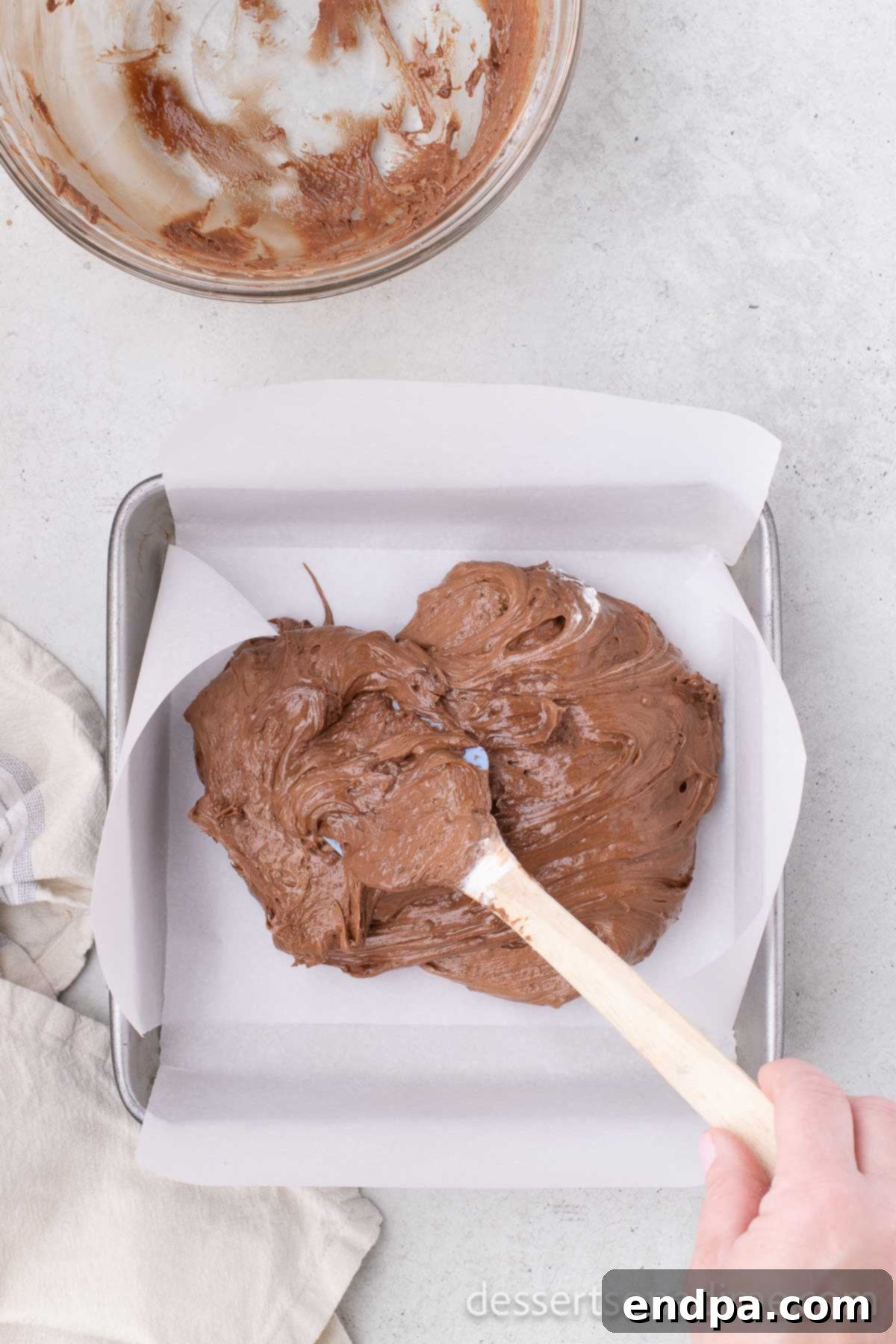Chocolate and Cool Whip mixture poured into a parchment-lined pan.