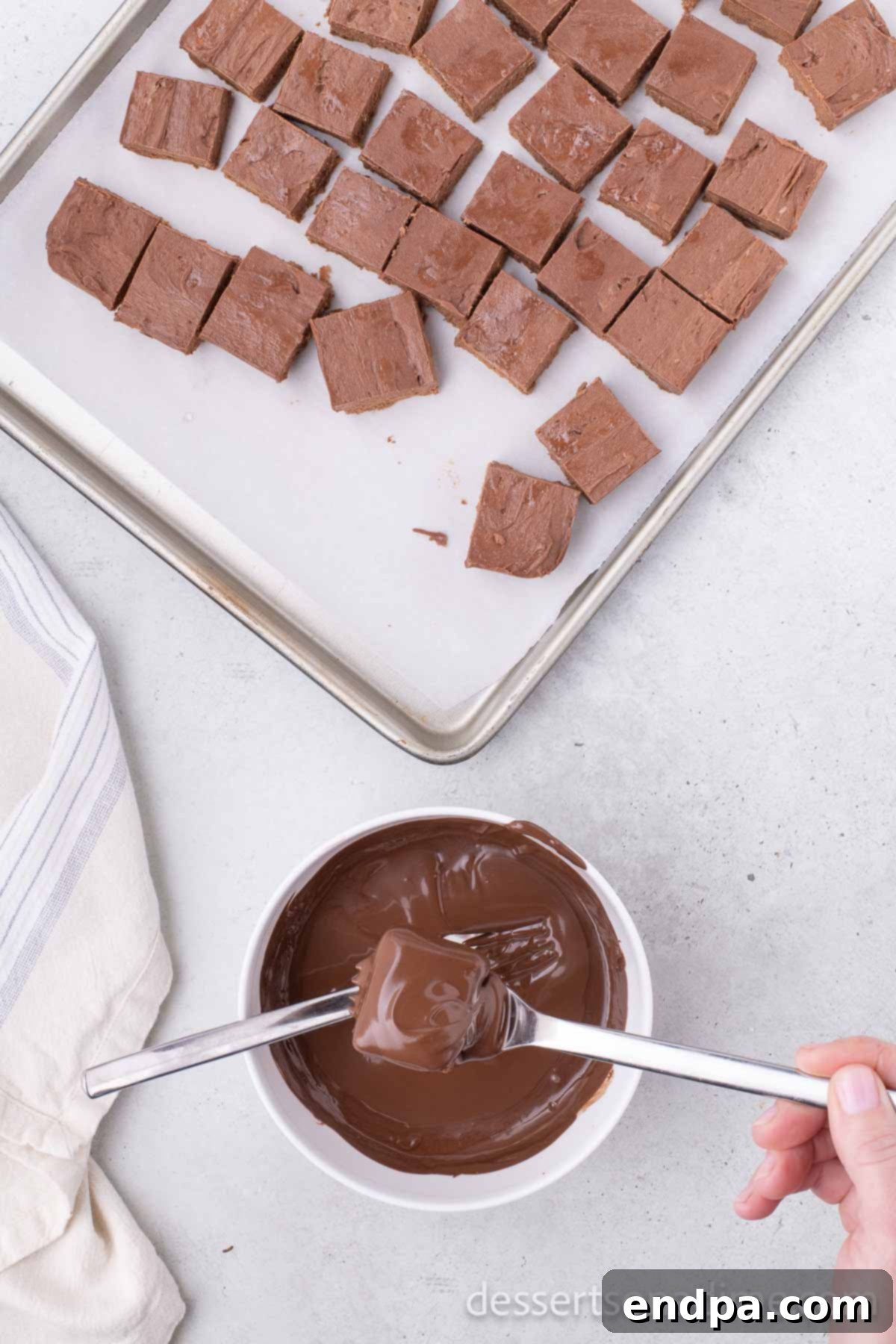 Chocolate squares being dipped into melted chocolate using two forks.