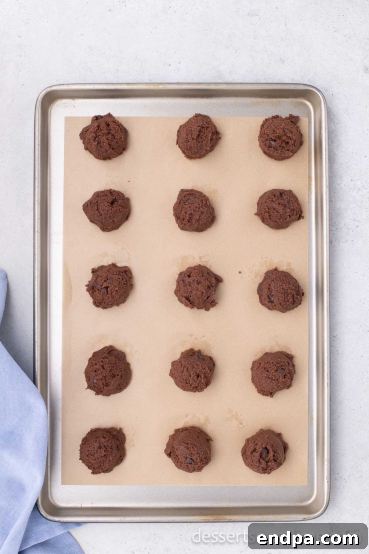 Portioned Nutella cookie dough balls neatly arranged on a parchment-lined baking sheet, spaced out for even baking.
