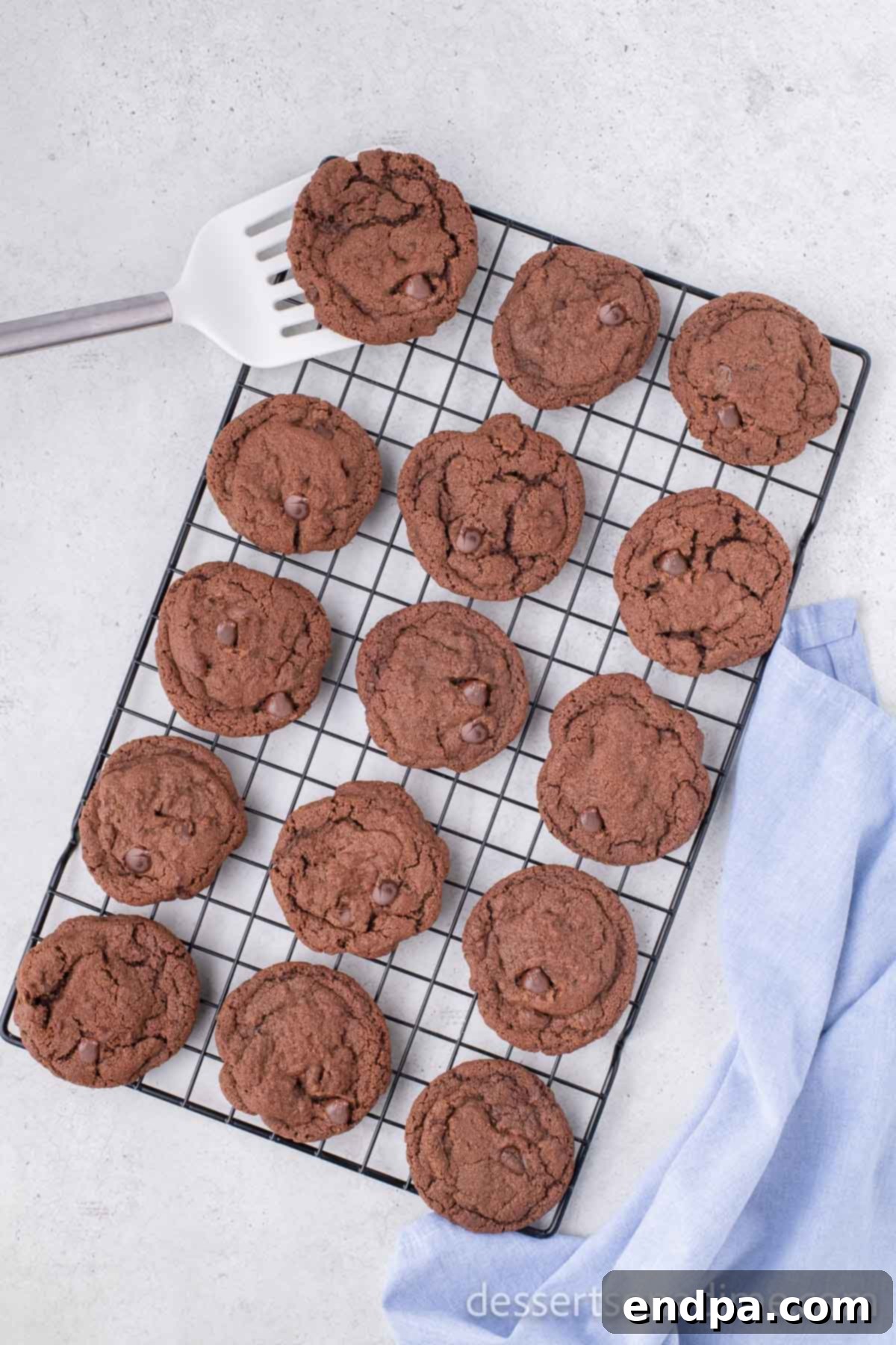 Warm Nutella cookies cooling on a wire rack after being transferred from the baking sheet, allowing air circulation for even cooling.