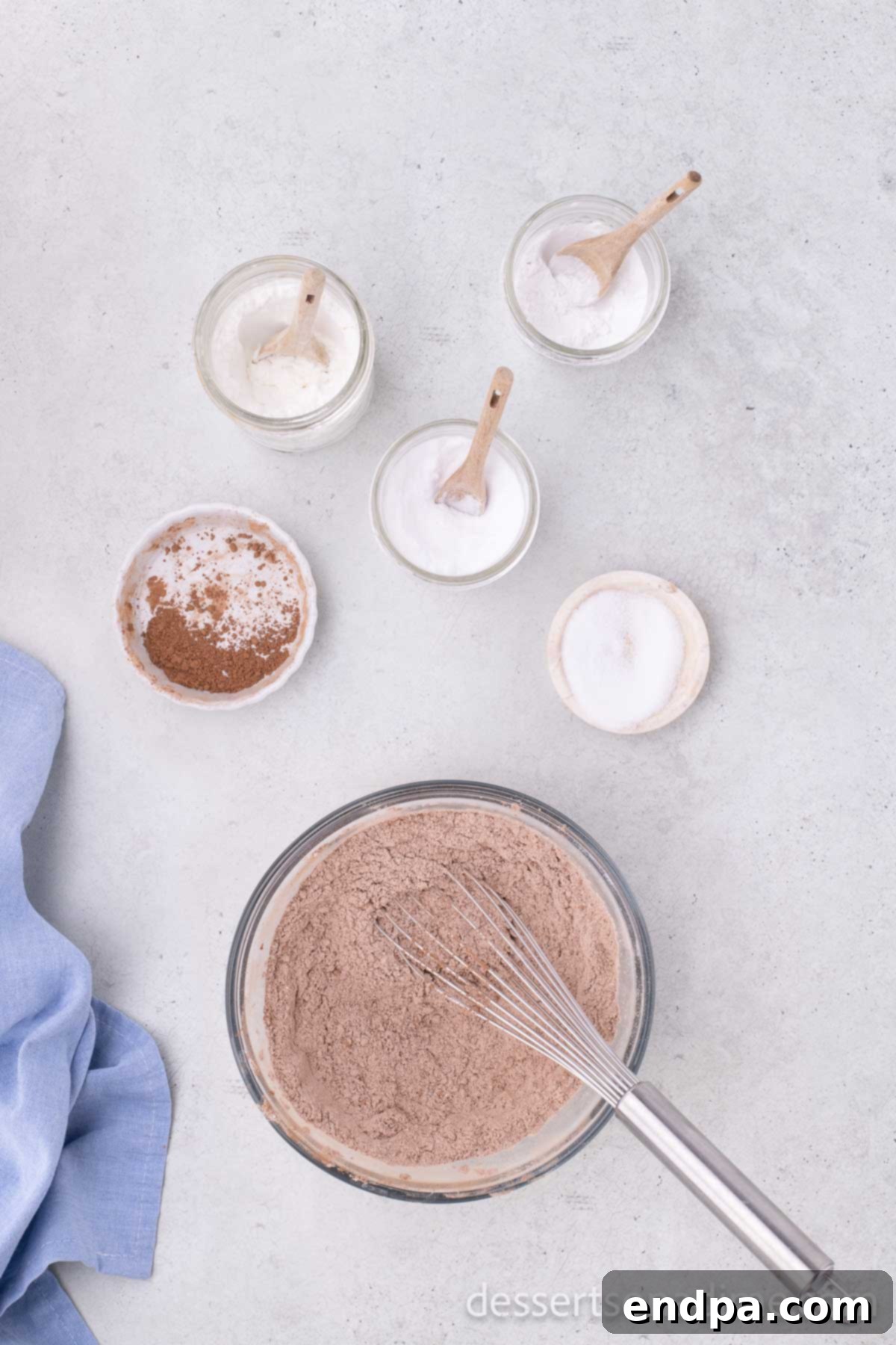 A mixing bowl containing all-purpose flour, cocoa powder, cornstarch, baking powder, baking soda, and salt, whisked together to combine the dry ingredients for the Nutella cookies.