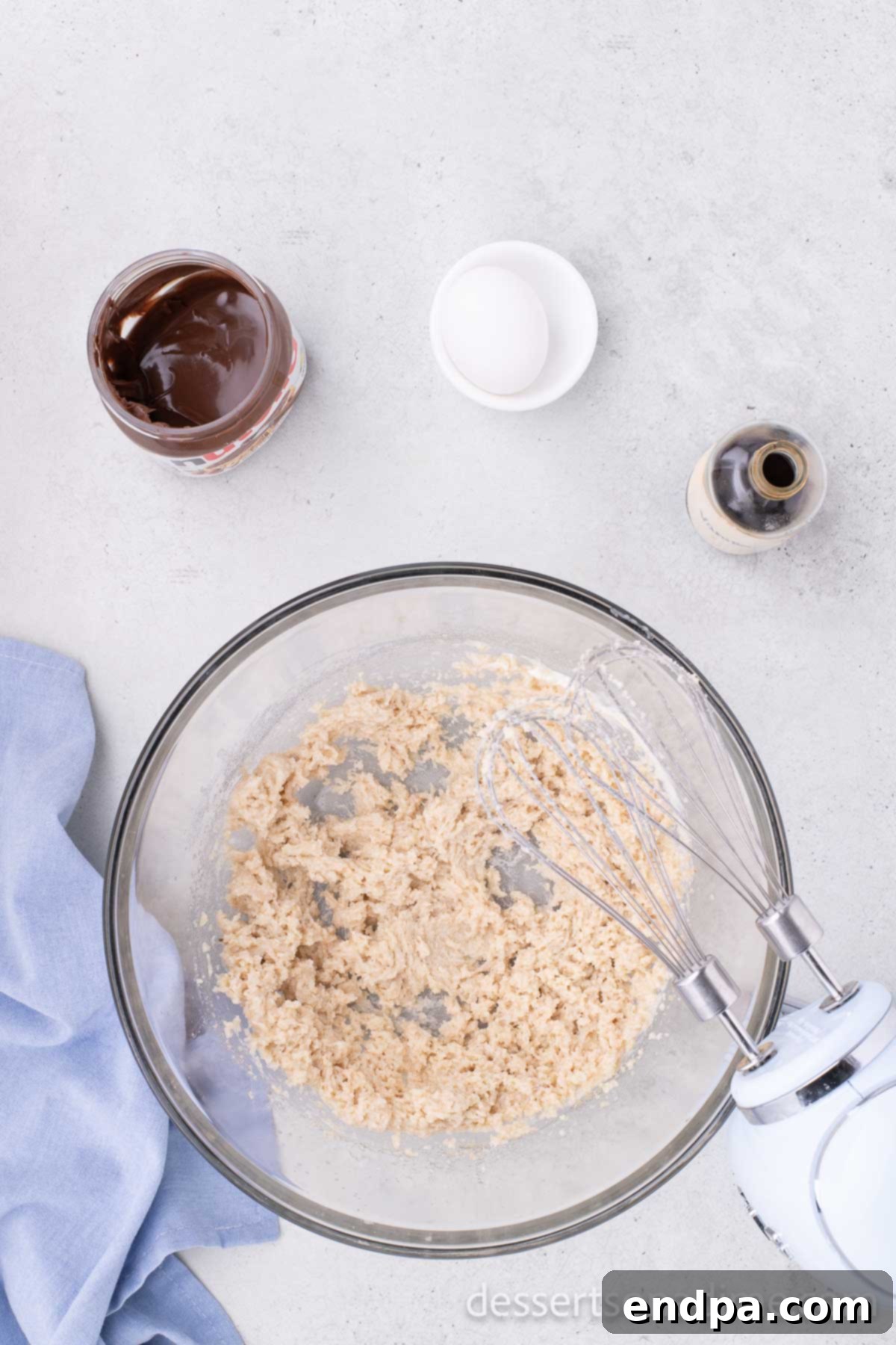 A separate mixing bowl with softened unsalted butter and both brown sugar and granulated sugar, beaten together until light and creamy for the Nutella cookie dough.