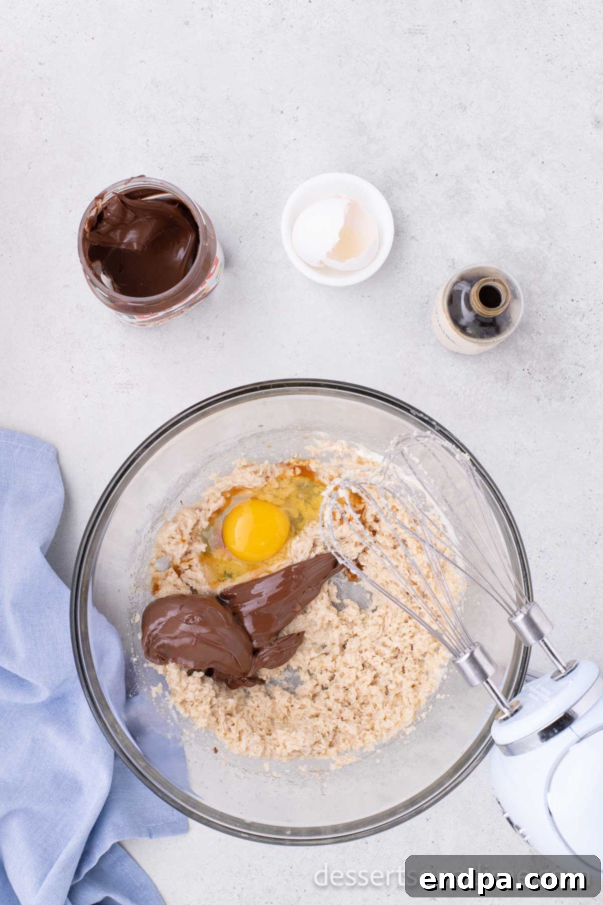 The butter and sugar mixture in a bowl after an egg, Nutella spread, and vanilla extract have been added and mixed in for the Nutella cookie dough.