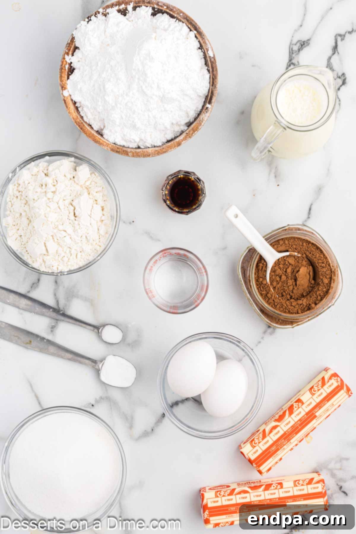 Texas Sheet Cake Minis 3 A selection of key ingredients for Texas Cake Bites laid out on a surface: flour, baking soda, butter, cocoa powder, buttermilk, and eggs.