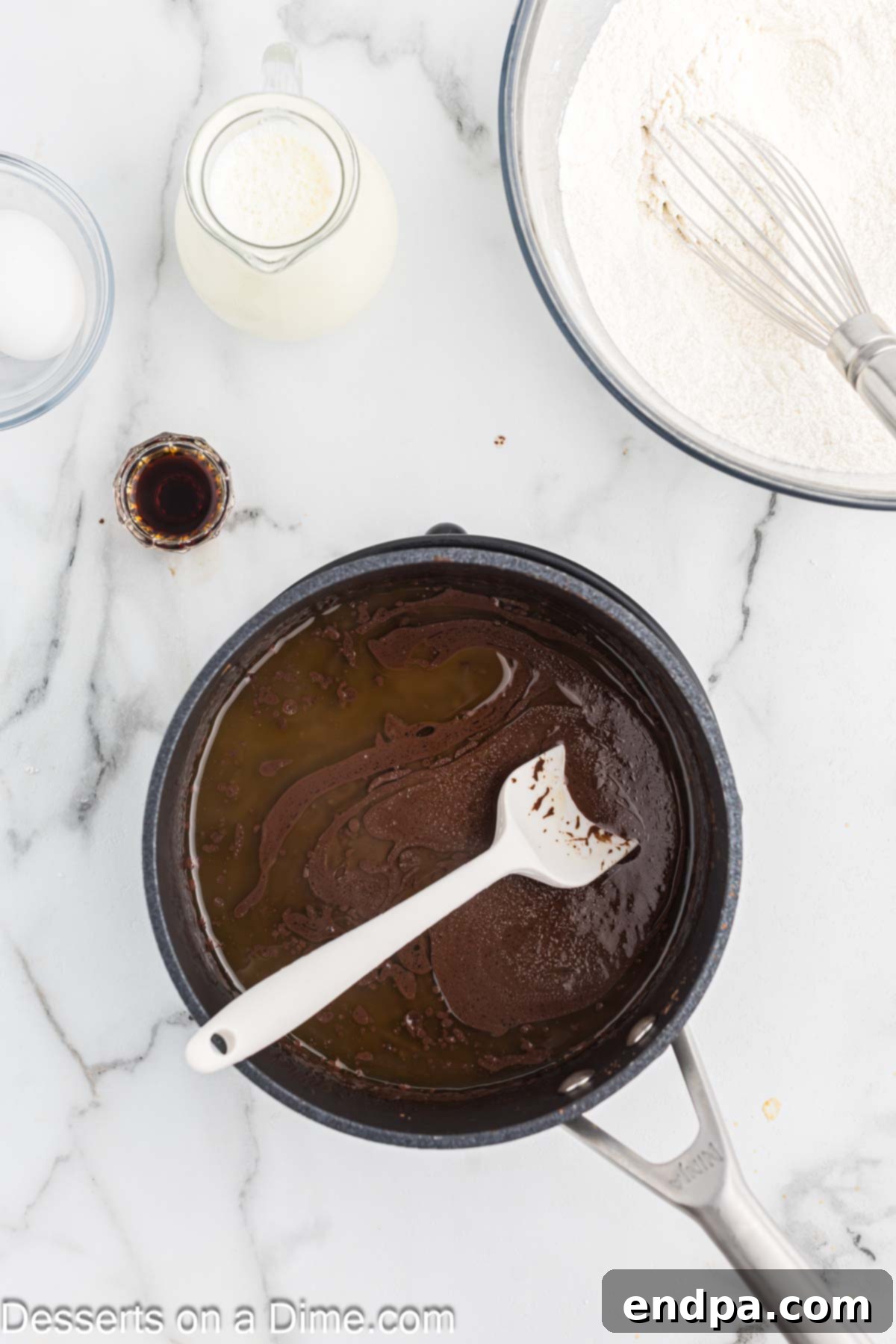 Texas Sheet Cake Minis 4 A saucepan on a stovetop, containing a mixture of cocoa powder, water, and butter, actively heating.