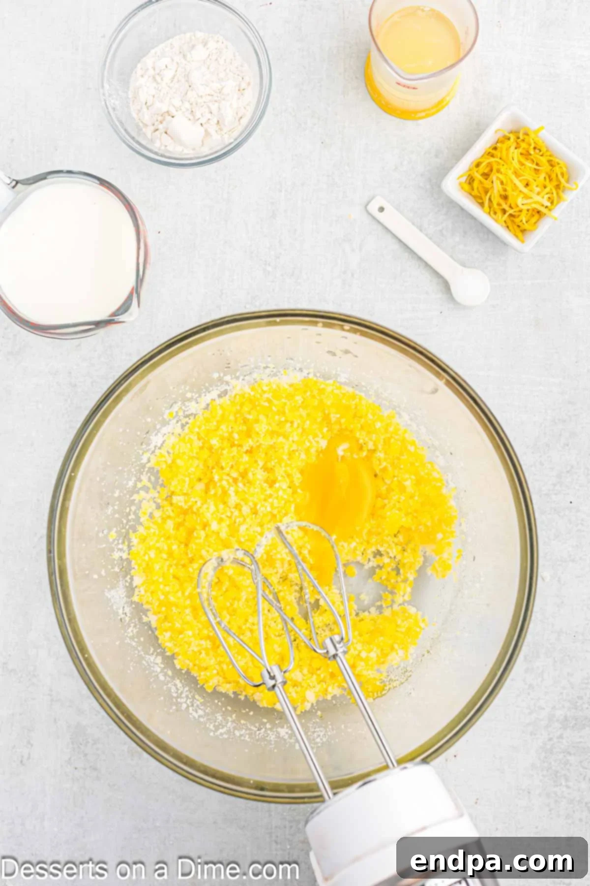 Adding egg yolks one at a time to the creamed butter and sugar mixture.