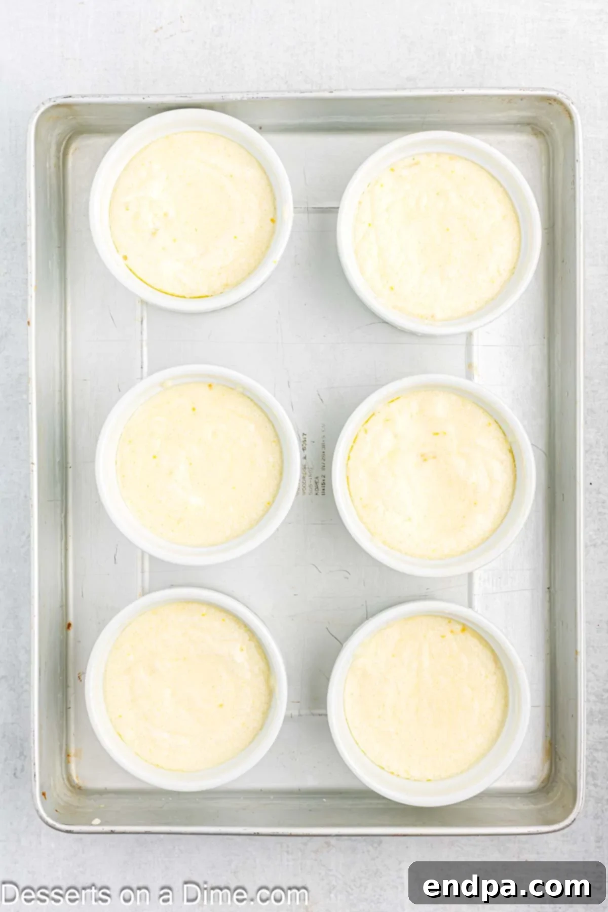 Pouring the lemon pudding cake batter into prepared ramekins for baking.