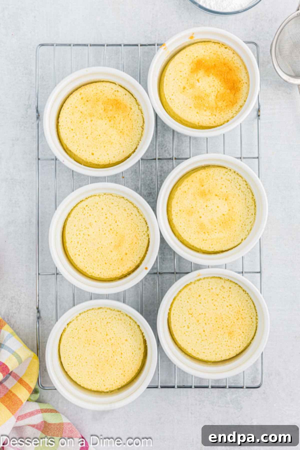 Baked lemon pudding cakes cooling on a wire rack after being removed from the water bath.