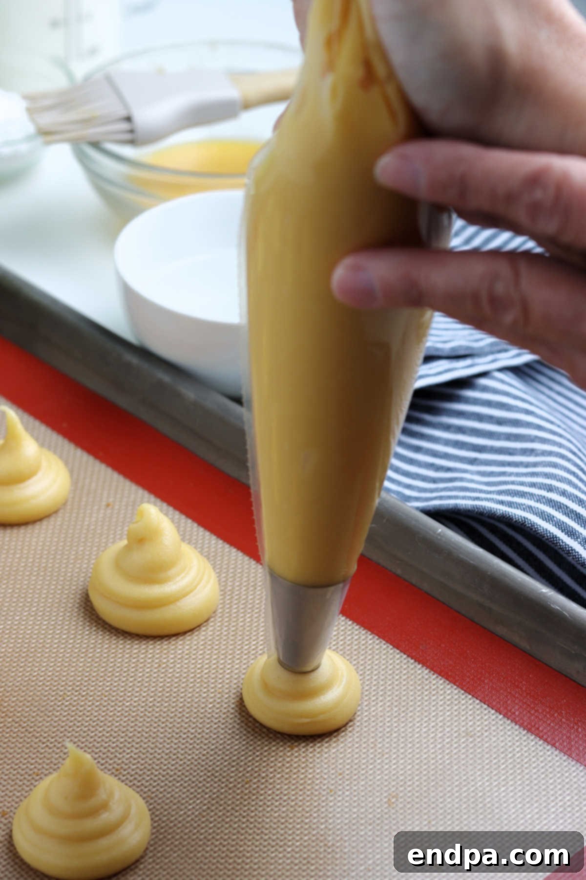 Irresistible Cream Puffs 4 Pastry bag with dough being piped onto a baking sheet, showing consistent circular shapes.