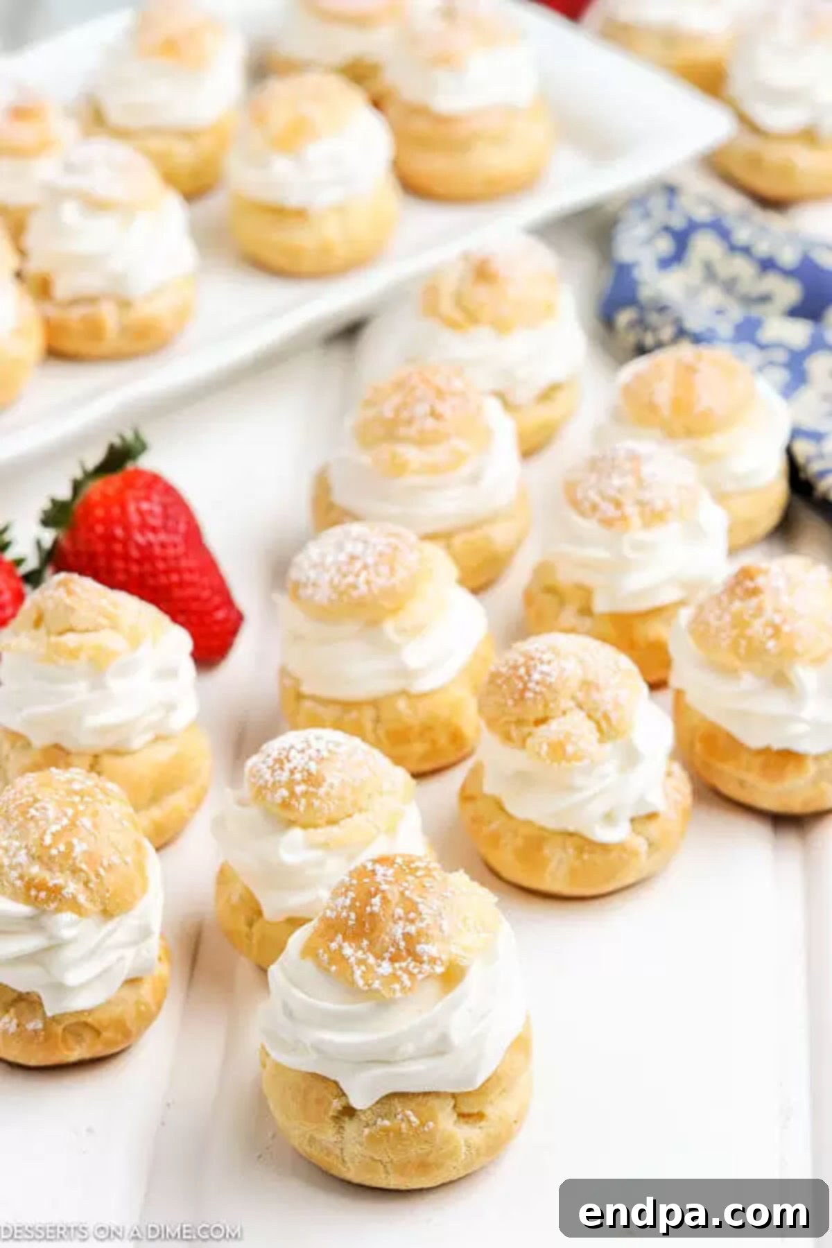 Irresistible Cream Puffs 7 Cream puffs stacked together on a plate, filled and ready to be served, dusted with powdered sugar.