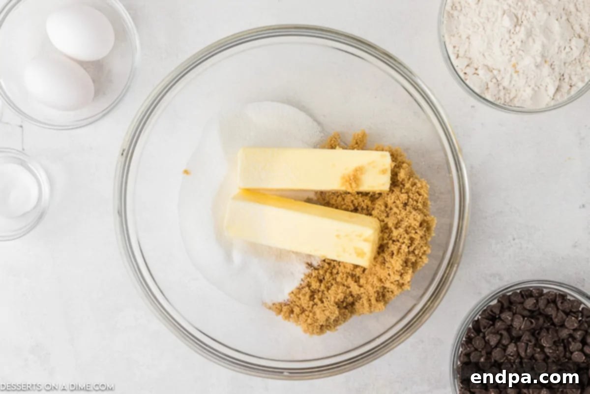A large mixing bowl with butter, sugar, brown sugar, and vanilla being beaten by a stand mixer until light and fluffy.