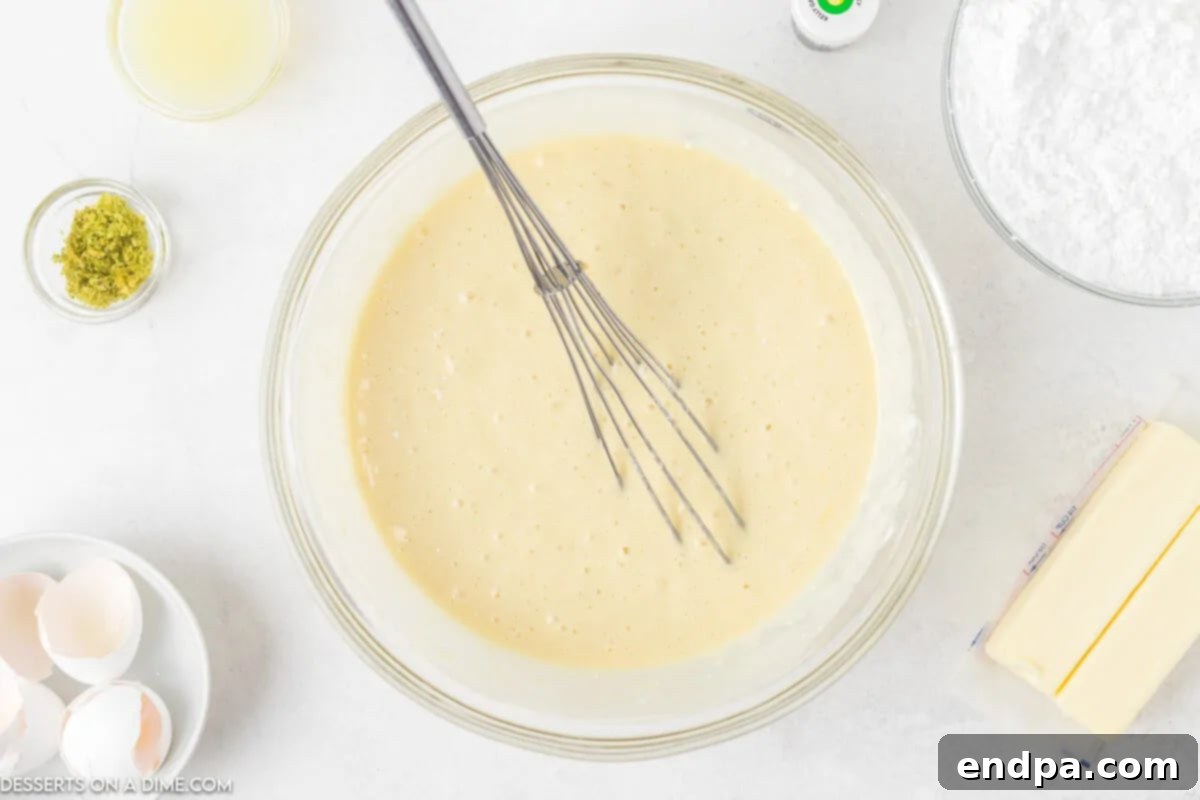 Mixing bowl with cake batter combined using an electric mixer, showing a smooth, light mixture.