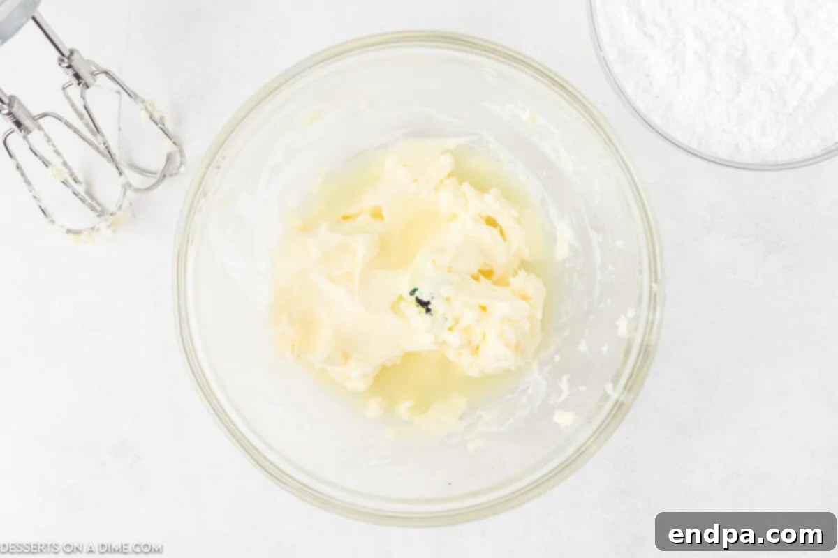 Softened butter being creamed in a large mixing bowl until it is light and fluffy.