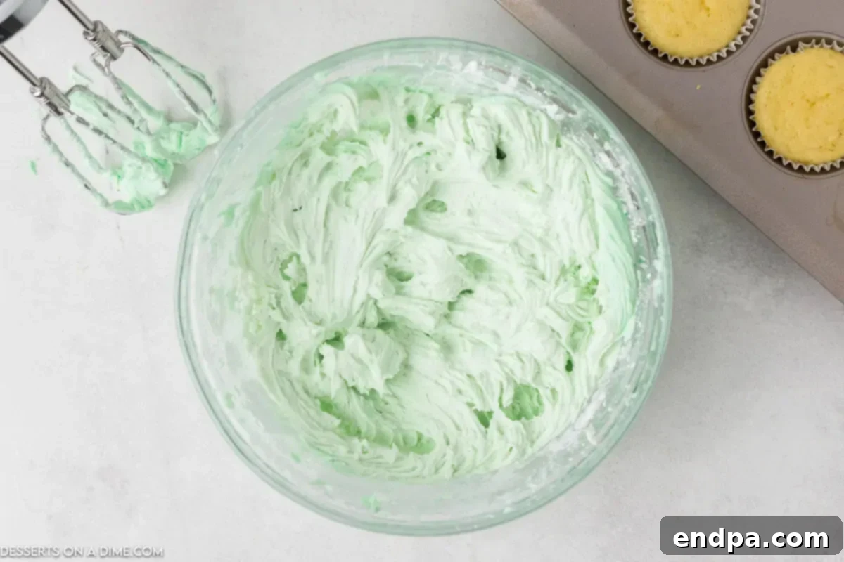 Lime juice and a drop of green food coloring being incorporated into the butter mixture for the frosting.