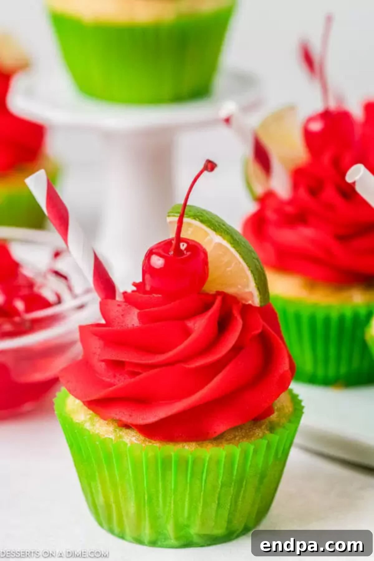 A perfect Cherry Limeade Cupcake: tangy lime cake, sweet cherry frosting, and refreshing garnishes for a delightful summer treat. Close-up of a beautifully frosted Cherry Limeade Cupcake, adorned with a fresh lime wedge and a maraschino cherry, ready to be enjoyed.