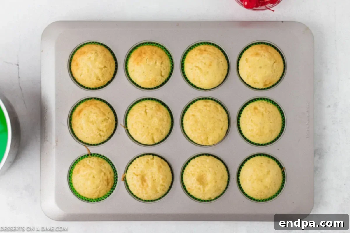 Zingy Cherry Limeade Cupcakes 3 A batch of freshly baked cupcakes cooling inside a muffin tin, positioned on a wire rack for proper air circulation.