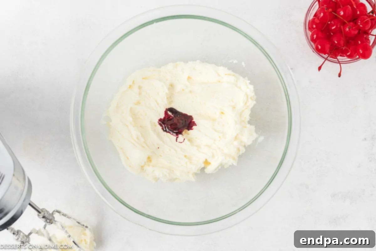 Zingy Cherry Limeade Cupcakes 8 Cherry extract and concentrated red food coloring being carefully added to the creamy white buttercream frosting in a mixing bowl.