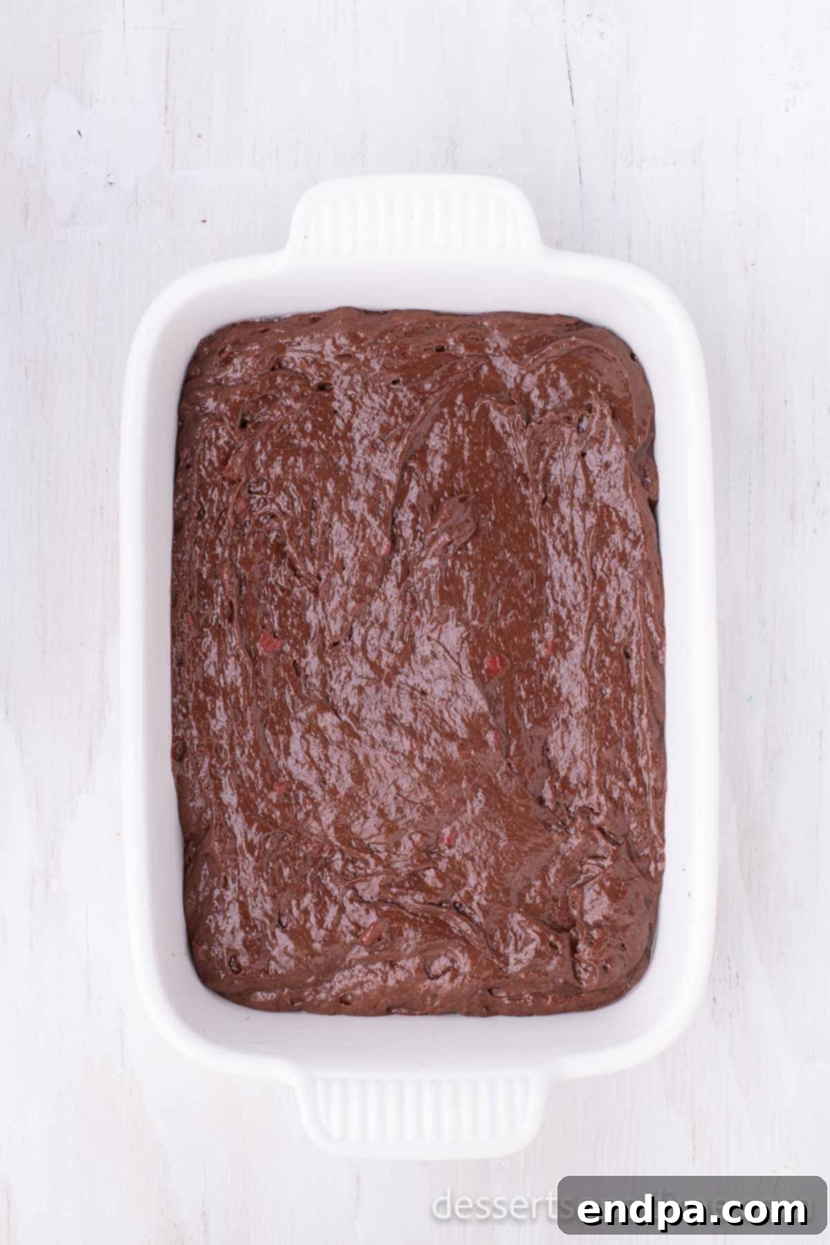 Decadent Chocolate Cherry Delight 3 A close-up shot of the chocolate cherry cake batter being mixed in a bowl, showing the streaks of red cherry pie filling blending with the dark chocolate cake mix.