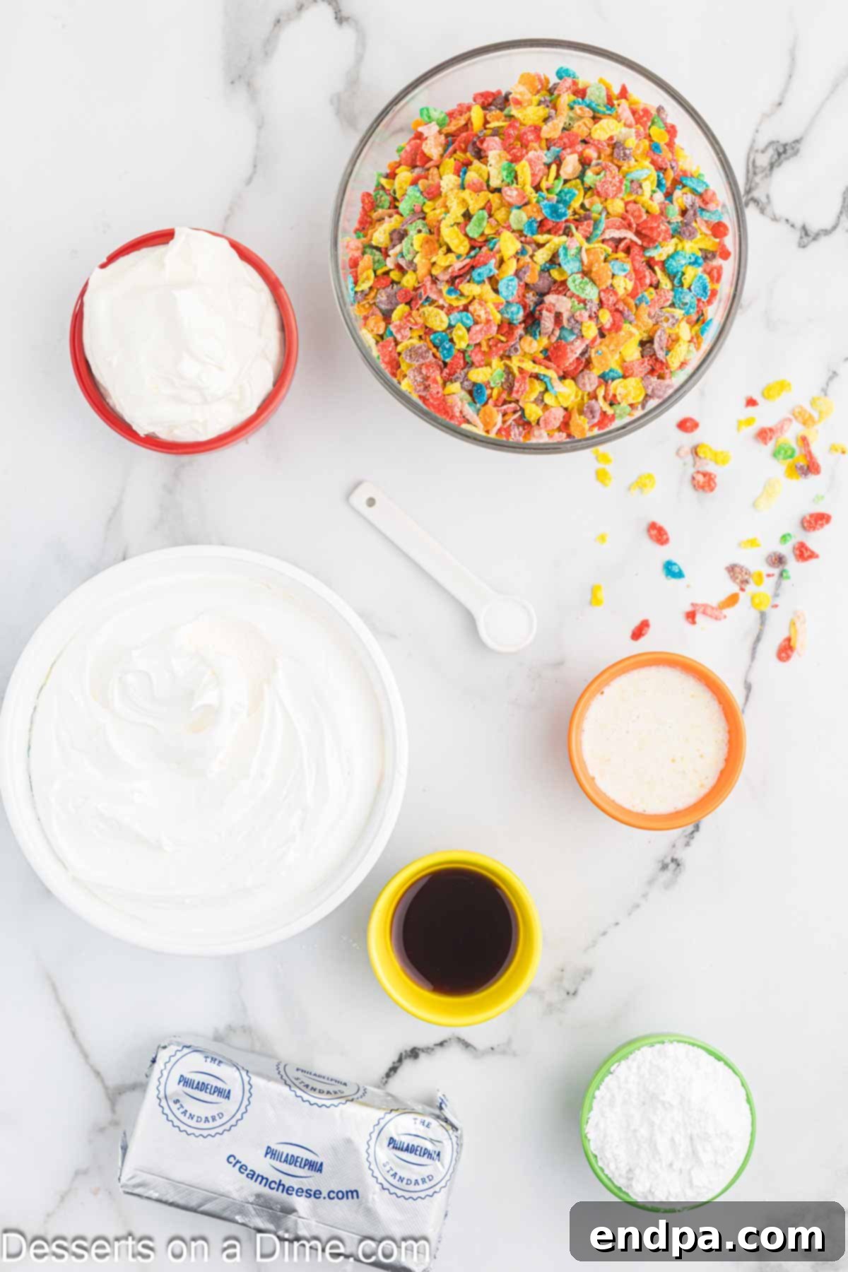 Vibrant Fruity Pebbles Cheesecake 3 A flat lay photograph showcasing all the ingredients for Fruity Pebbles Cheesecake, including Fruity Pebbles cereal, butter, blocks of cream cheese, a tub of sour cream, powdered sugar, vanilla extract, and a container of Cool Whip.