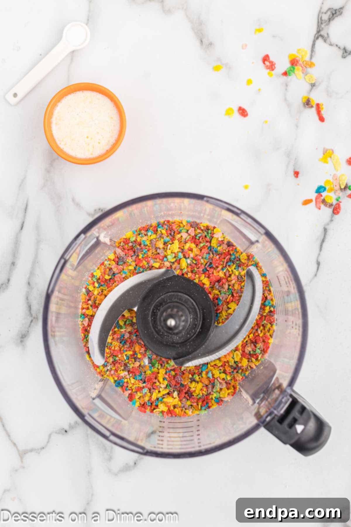 Vibrant Fruity Pebbles Cheesecake 4 Fruity Pebbles cereal being processed in a food processor to create fine crumbs for the cheesecake crust.