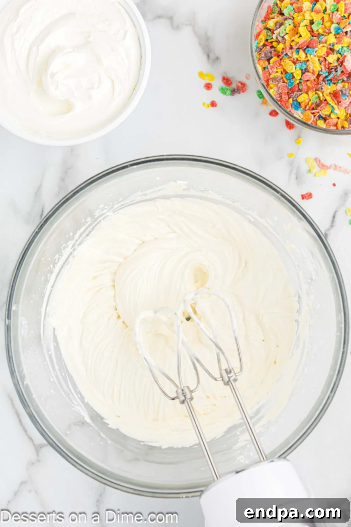 Vibrant Fruity Pebbles Cheesecake 6 A large mixing bowl containing whipped cream, ready to be incorporated into the cheesecake filling.