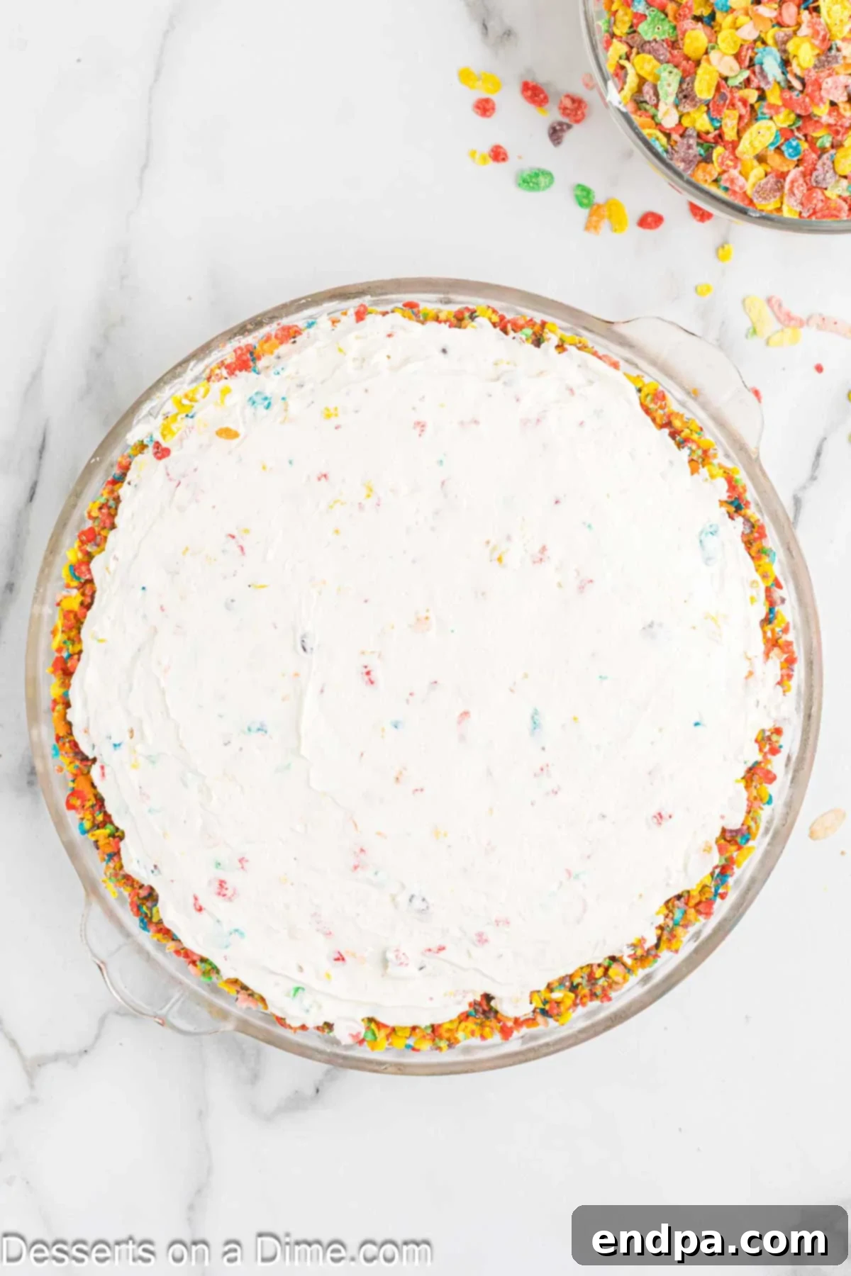 Vibrant Fruity Pebbles Cheesecake 8 The creamy cheesecake mixture spread evenly over the set Fruity Pebbles crust in a pie pan, ready for chilling.