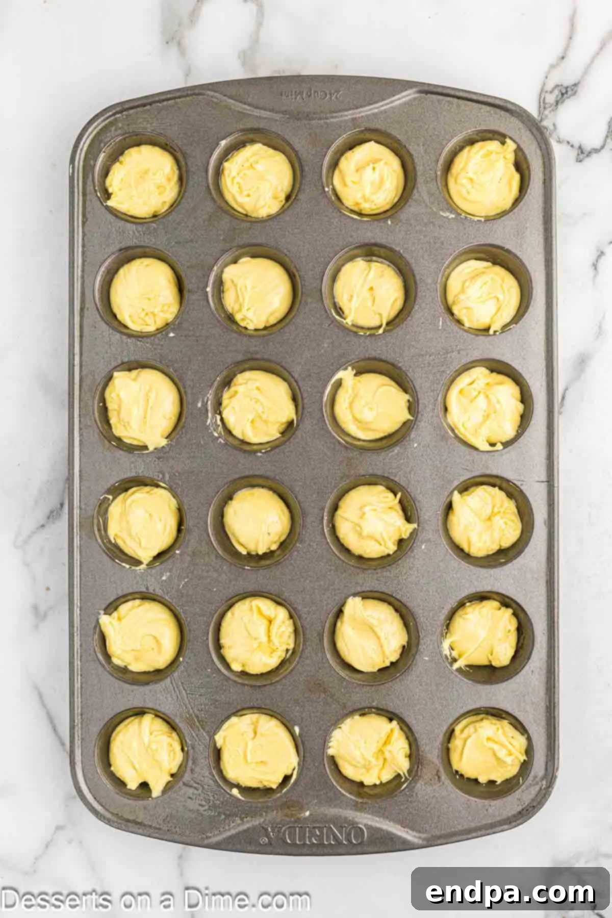 Pouring lemon blossom batter into mini muffin tins.