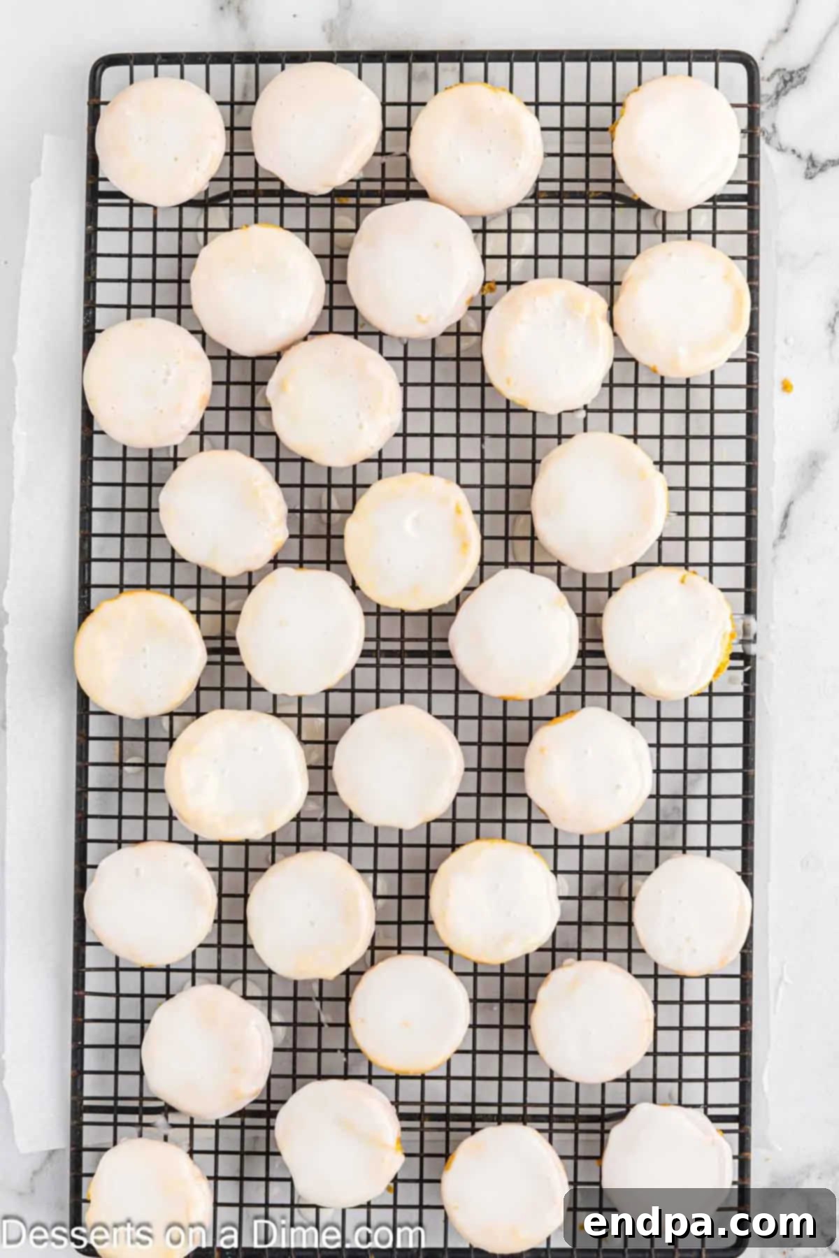 Dipping warm Lemon Blossoms into a vibrant lemon glaze.