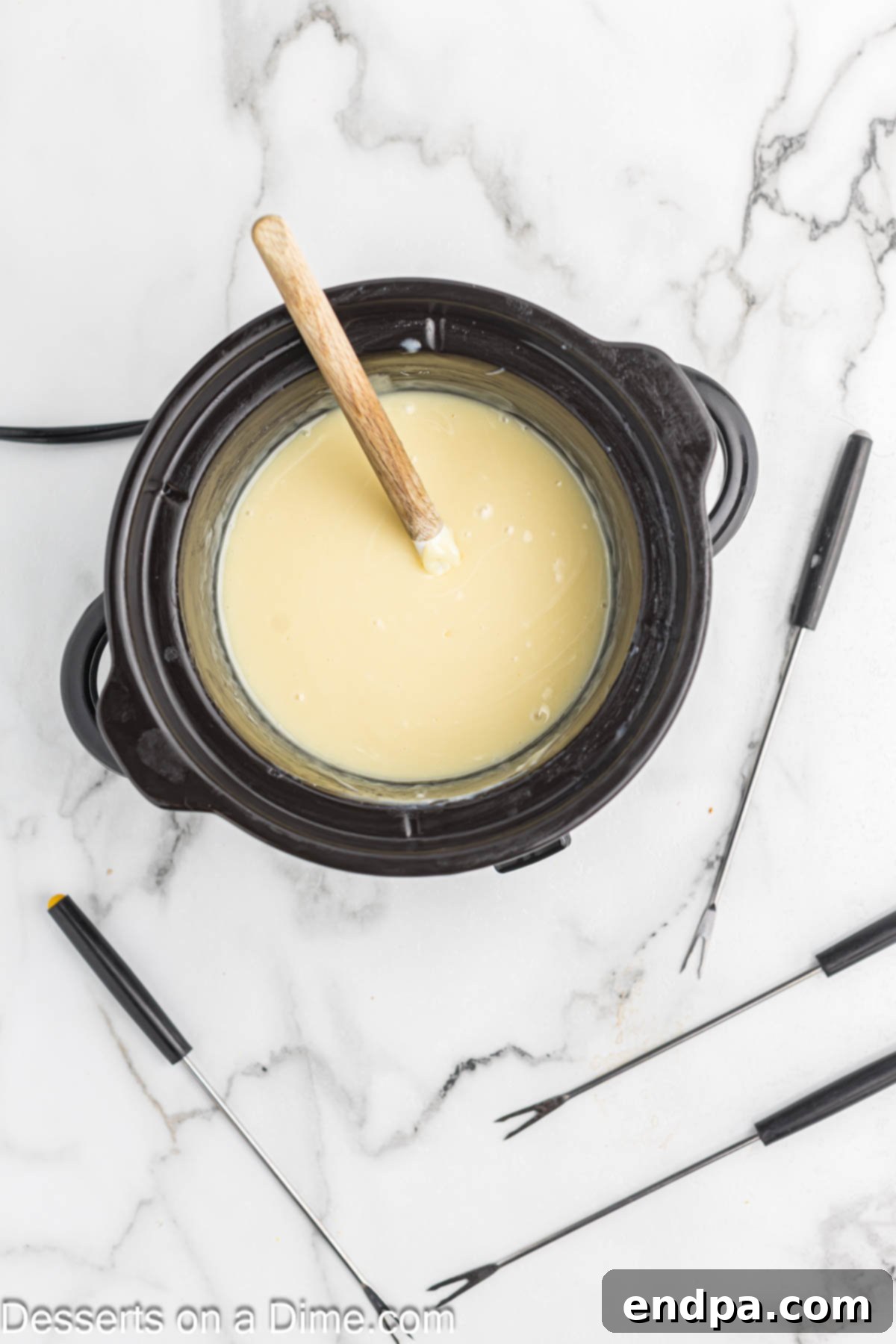 Decadent White Chocolate Fondue 4 White chocolate, heavy cream, coconut oil, and salt melting gently together in a fondue pot, creating a smooth mixture.