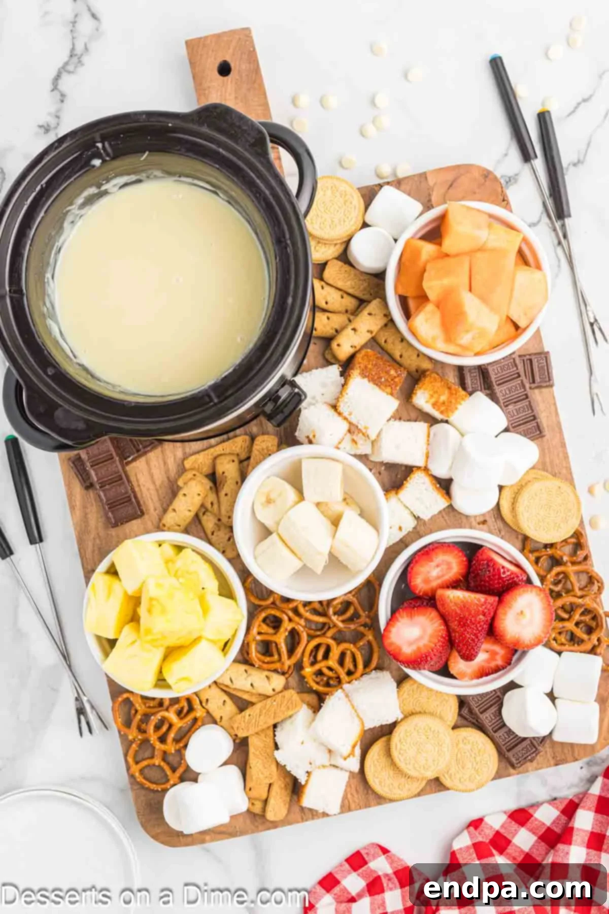 Decadent White Chocolate Fondue 5 A fondue pot filled with creamy white chocolate fondue, surrounded by a delightful selection of dippers like fresh fruit and cookies, ready for guests to enjoy.