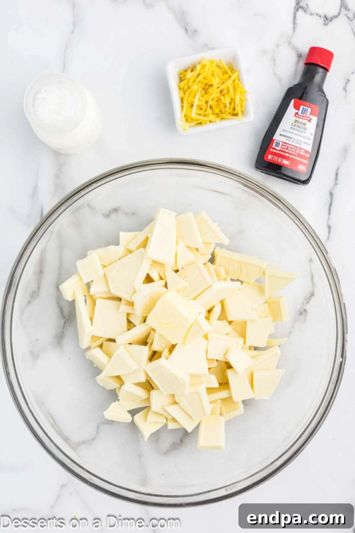 Mixing bowl with white chocolate baking bars broken into small pieces and butter.
