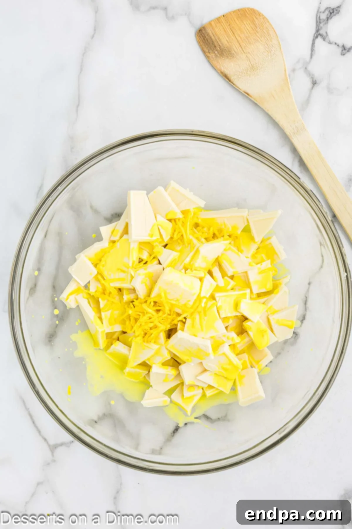 Hot lemon mixture poured over white chocolate and butter in a bowl.