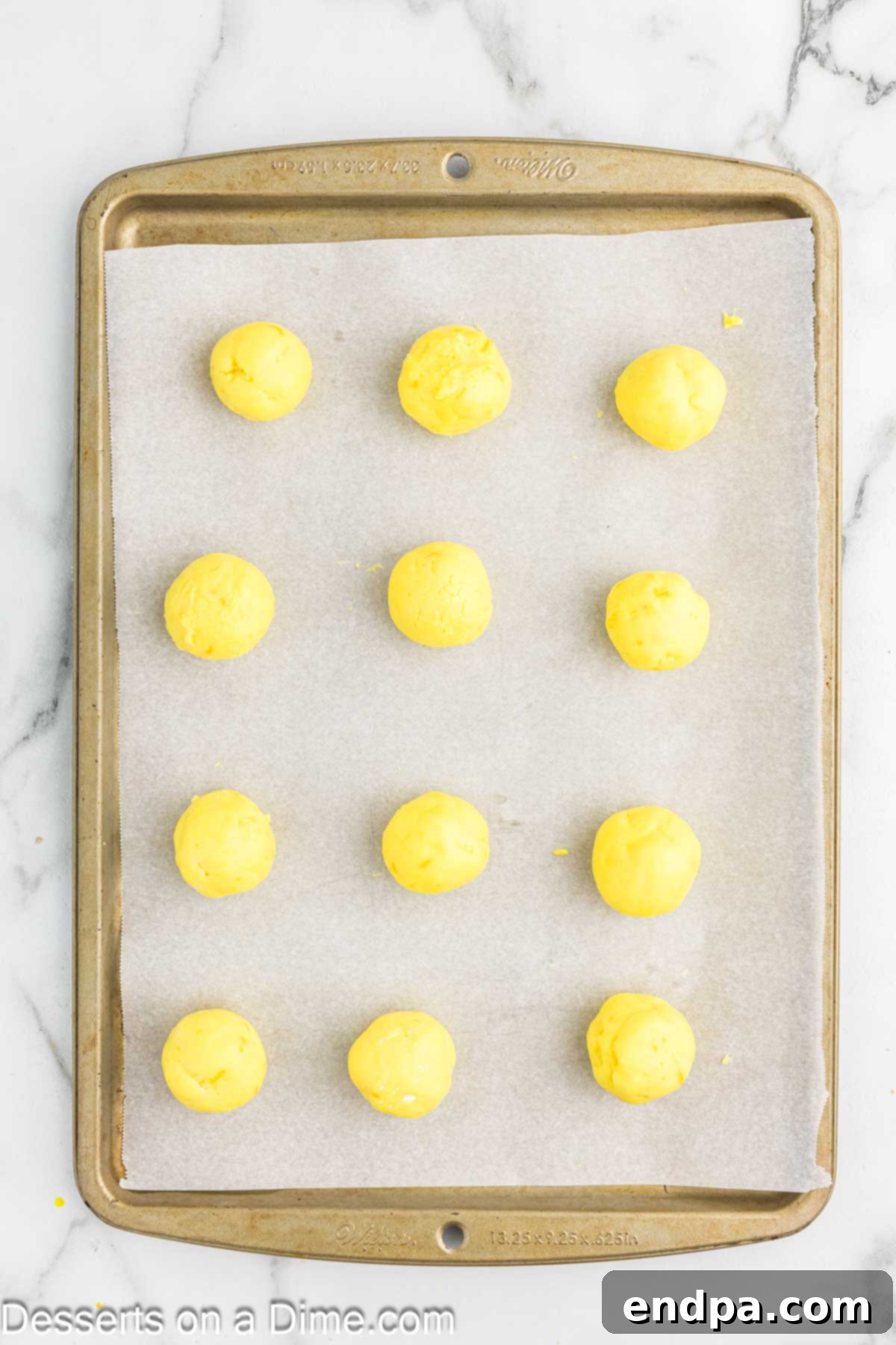 Lemon truffle mixture scooped and rolled into balls, placed on a baking sheet.