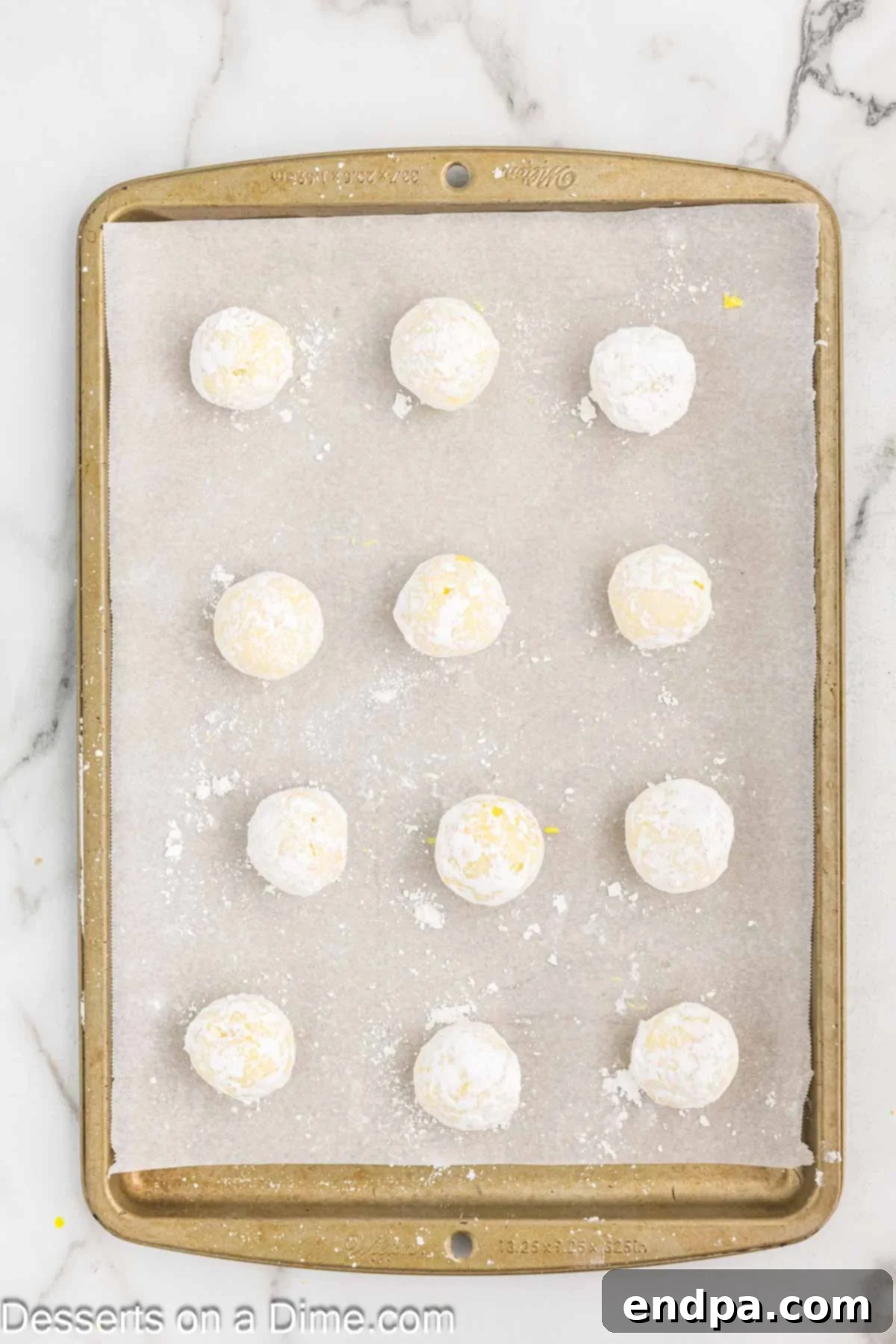 Lemon truffles coated in powdered sugar and arranged on a parchment-lined baking sheet.