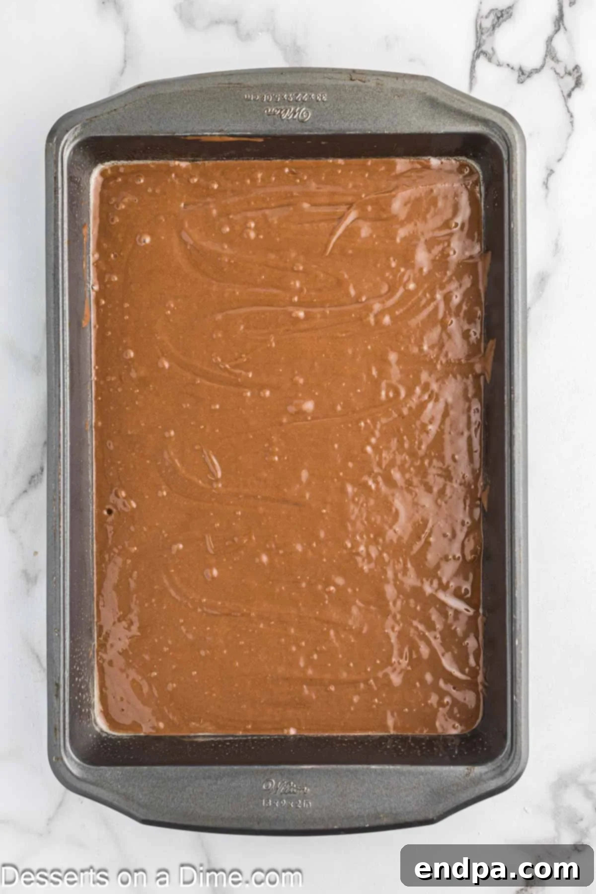 Chocolate mayonnaise cake batter poured into a greased cake pan.