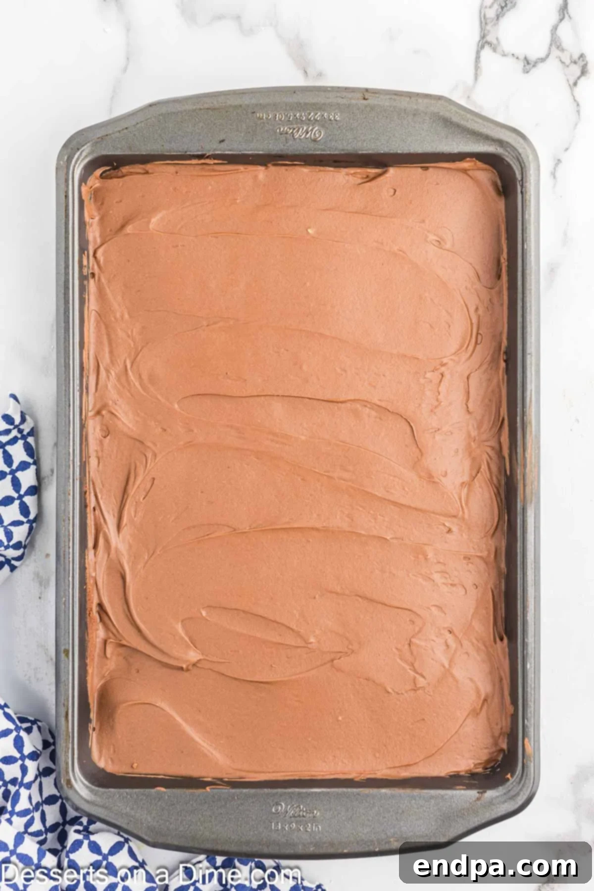 Rich chocolate frosting spread evenly on top of the cooled chocolate mayonnaise cake.