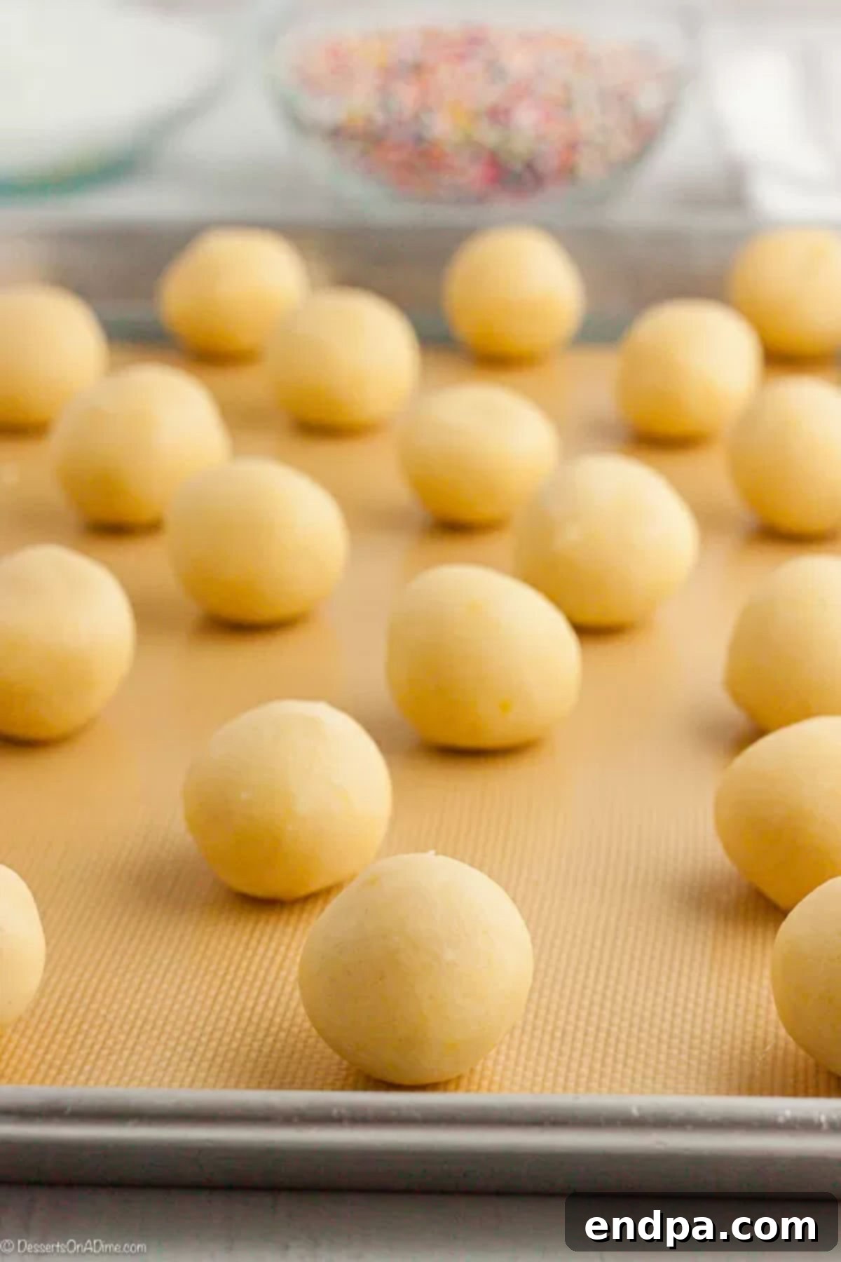 Uniformly shaped cookie dough balls neatly arranged on a baking sheet, chilled and ready for the oven.