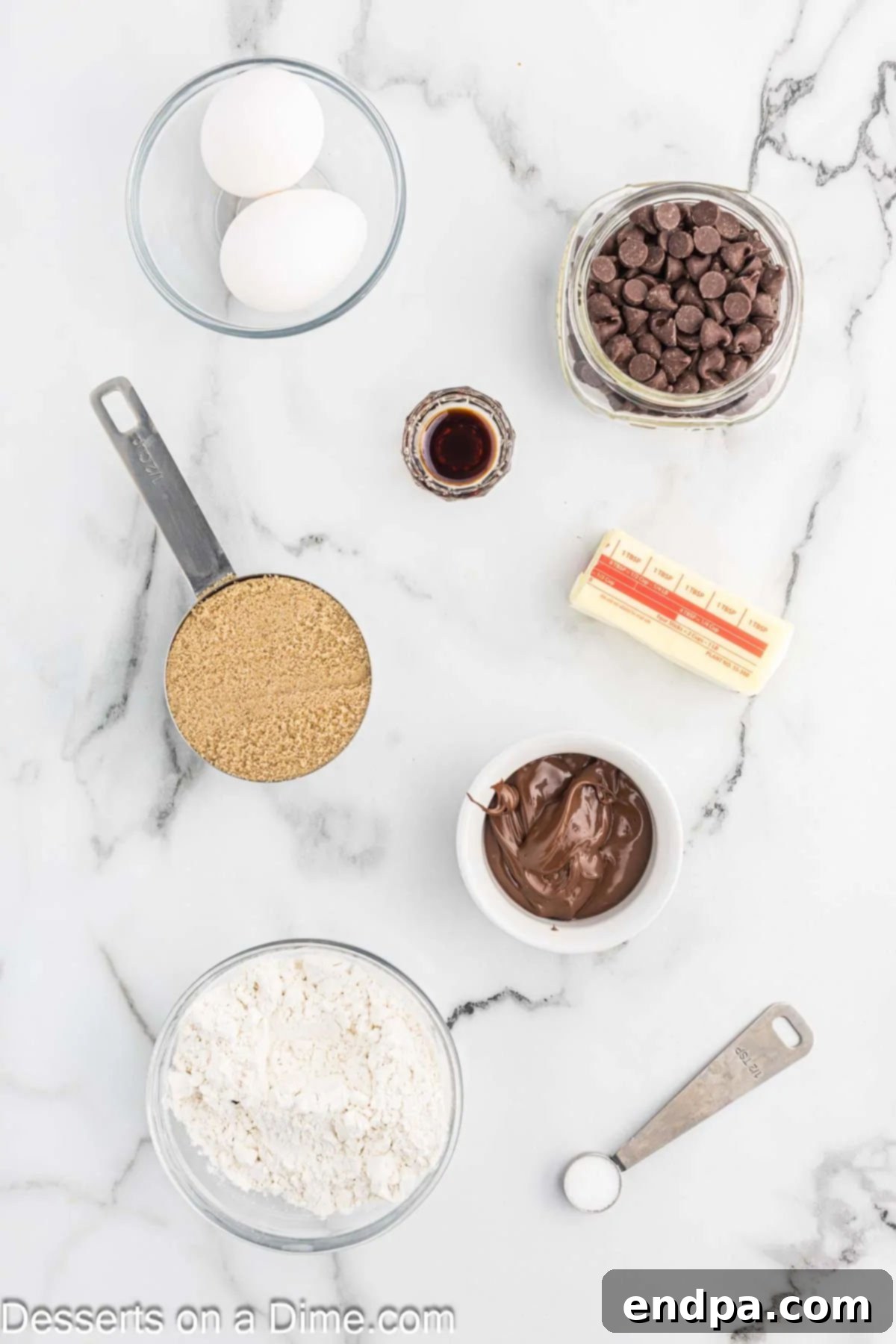 A flat lay image displaying all the essential ingredients for Nutella Brownies: softened unsalted butter, packed brown sugar, large room temperature eggs, pure vanilla extract, a jar of Nutella, all-purpose flour, and semi-sweet chocolate chips.