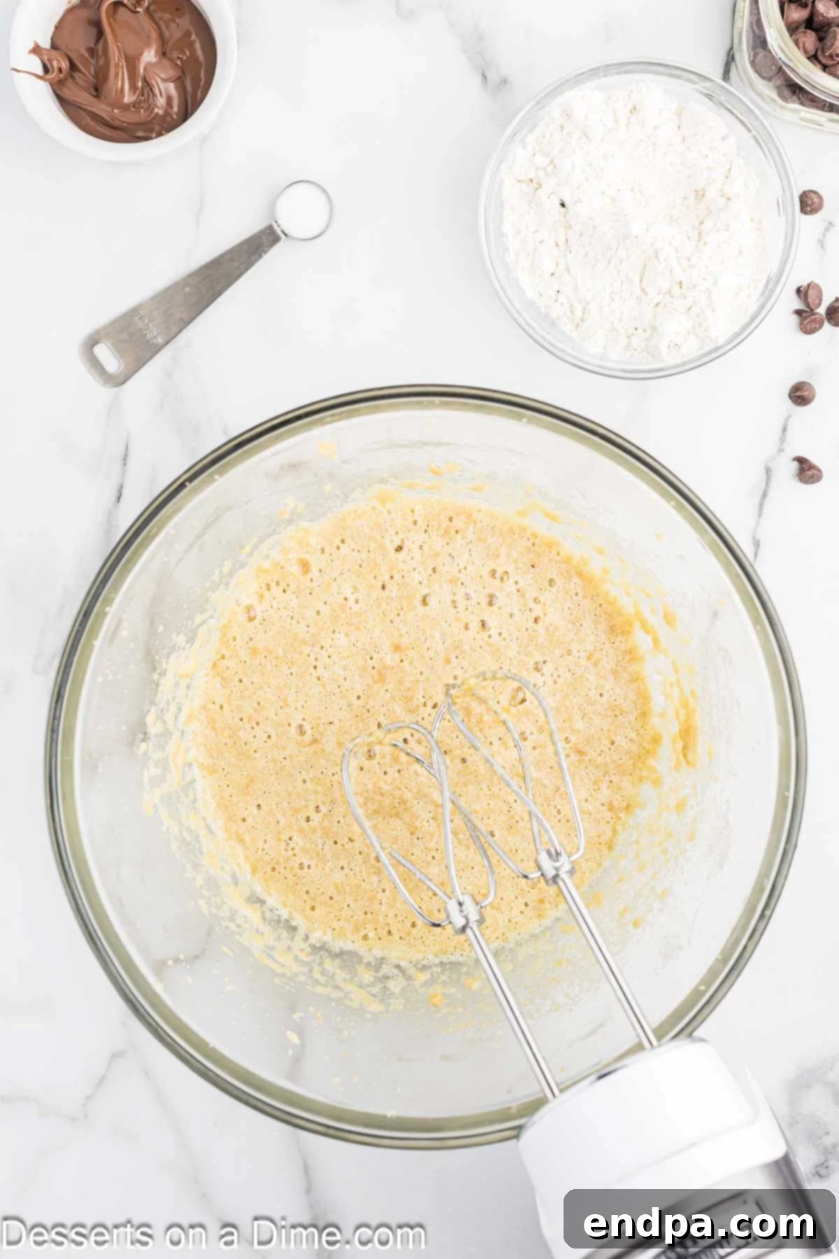 Room temperature eggs and vanilla extract being added to the creamed butter and brown sugar mixture in a bowl.