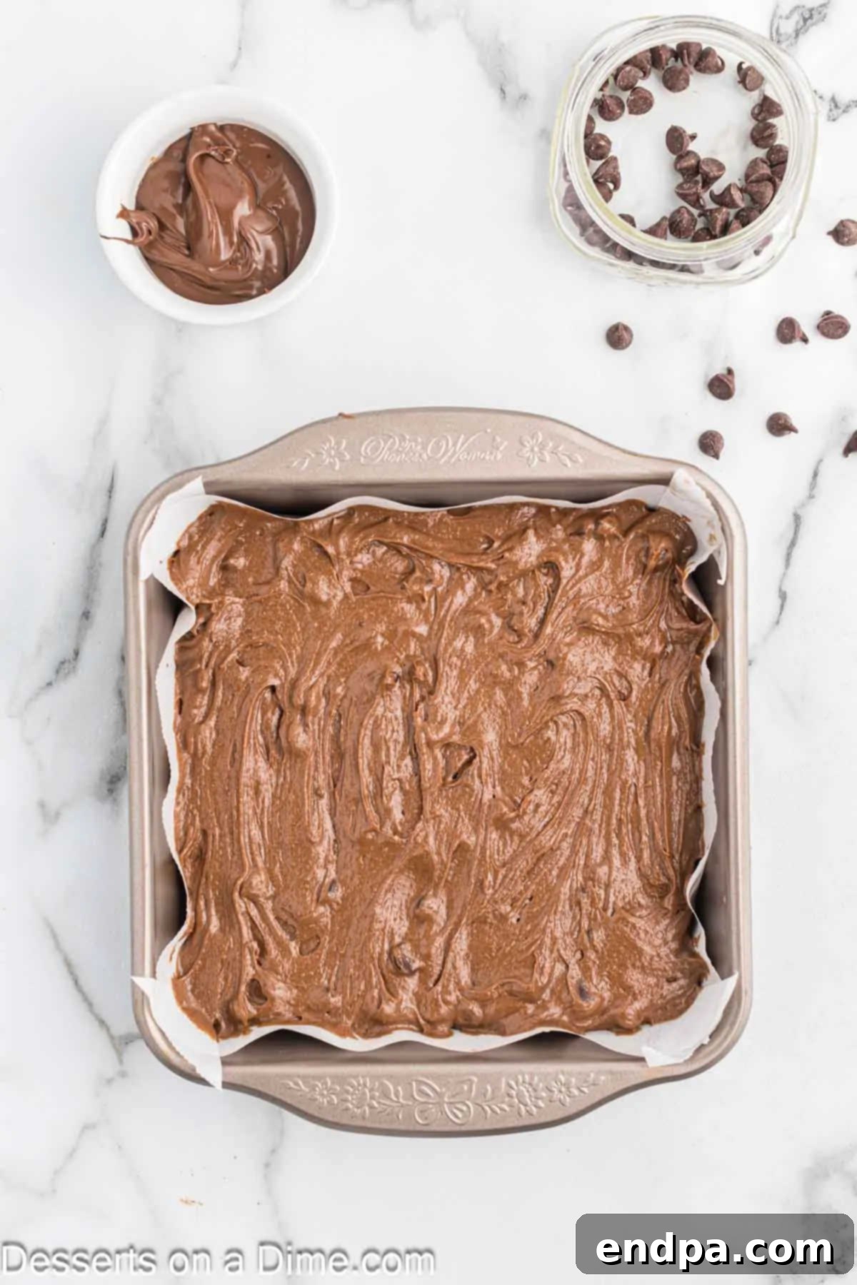 Smooth Nutella brownie batter spread evenly into a parchment-lined baking pan.