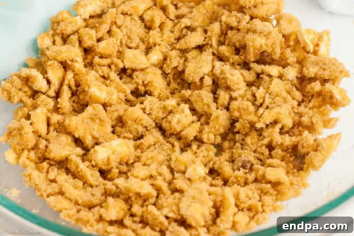 Softened butter and brown sugar are creamed together by hand in a large mixing bowl, showing a smooth, light brown mixture.